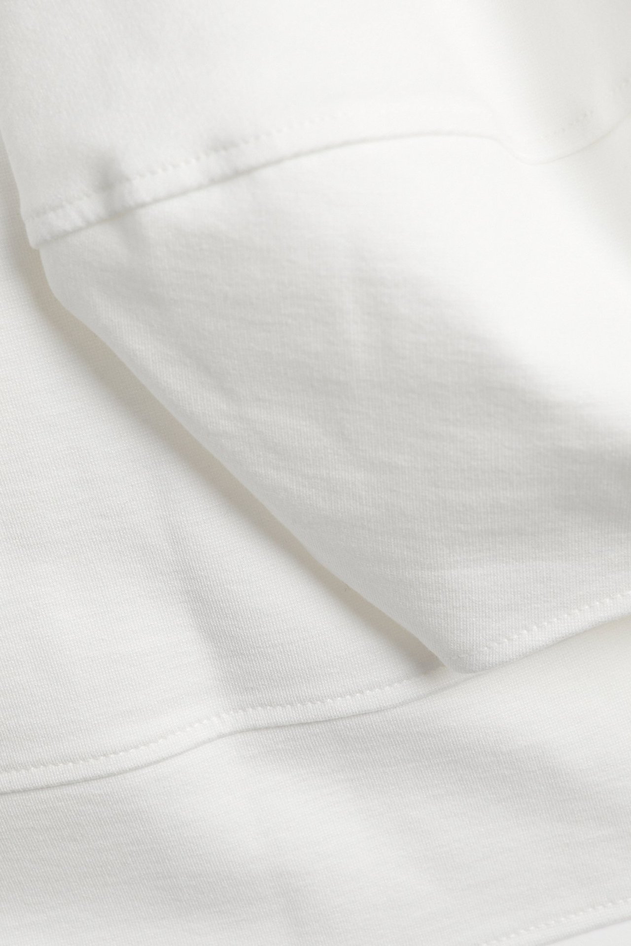 Zbliżenie na top punto w kolorze ecru, ukazujące gładką teksturę materiału i szyte szwy.