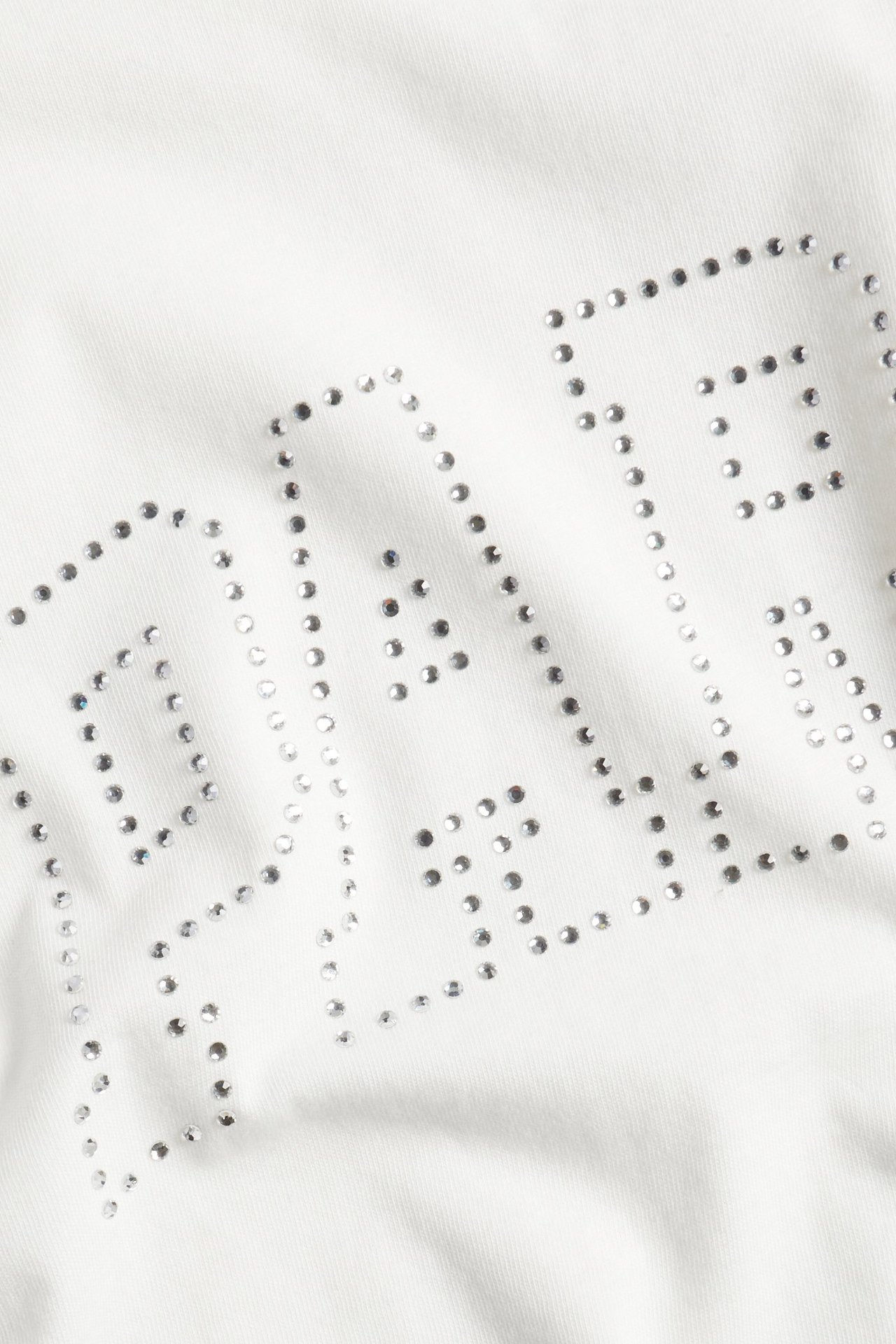 Zbliżenie na biały bawełniany T-shirt z błyszczącym nadrukiem z dżetów, tworzącym litery.