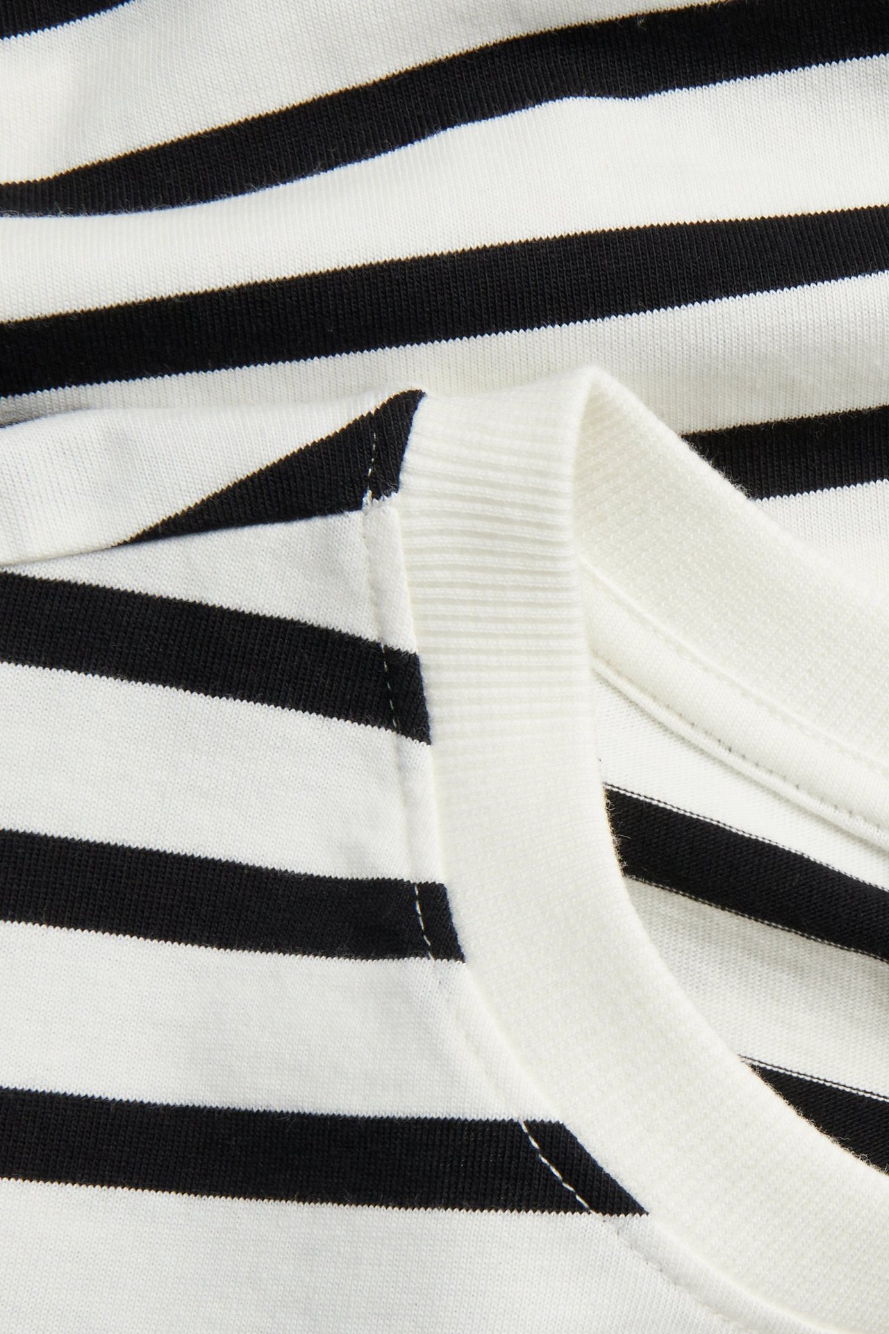 Lähikuva mustavalkoisesta raidallisesta puuvillaisesta t-paidasta pyöreällä pääntiellä.