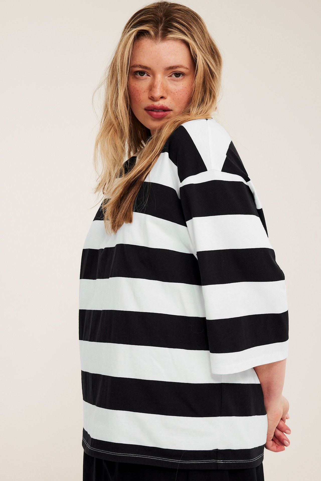 Sidebilde av en kvinne i en oversized svart og offwhite stripete bomulls t-skjorte.