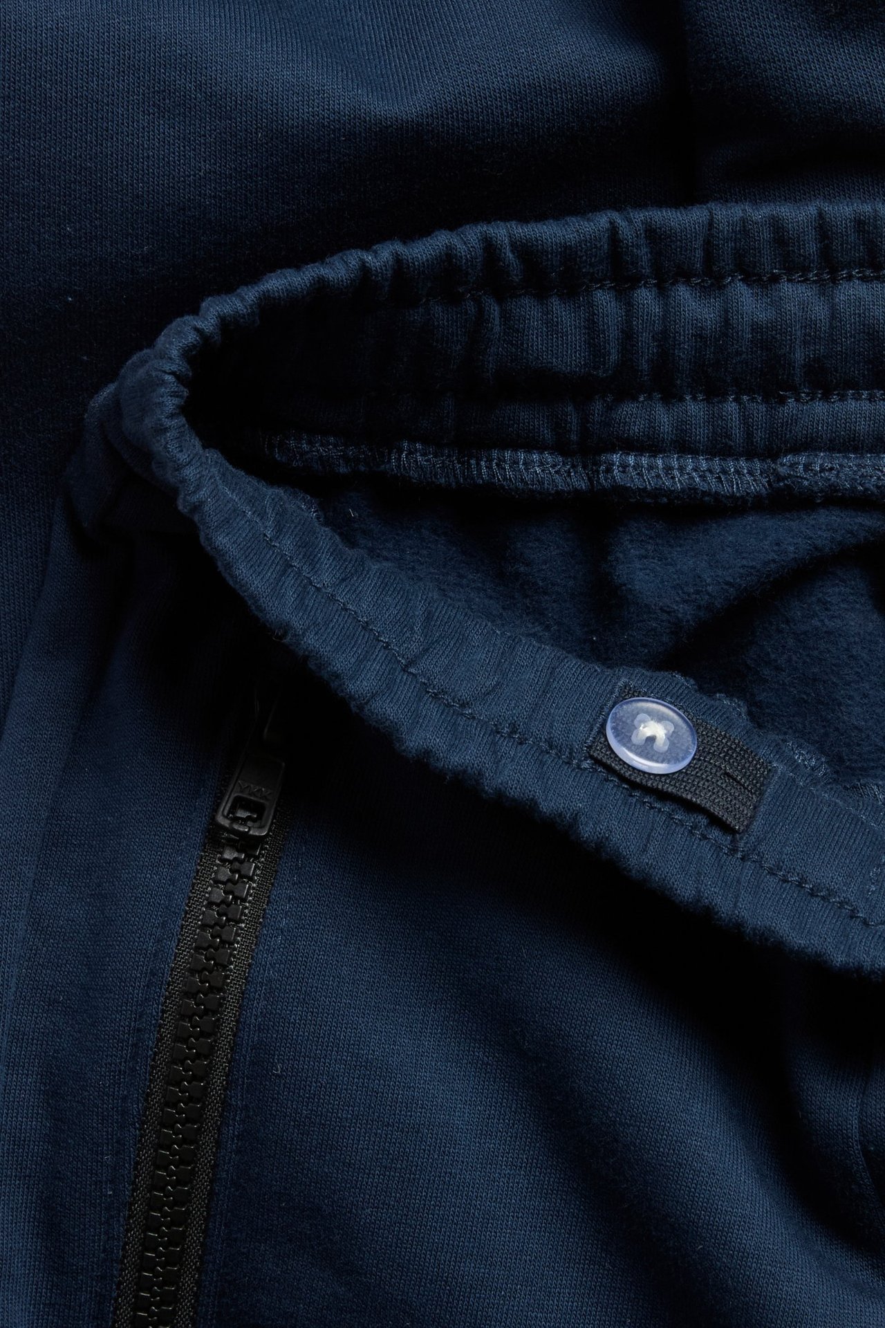 Zbliżenie: ciemnoniebieskie dresy bawełniane z regulowanym, prążkowanym pasem i kieszenią na zamek.