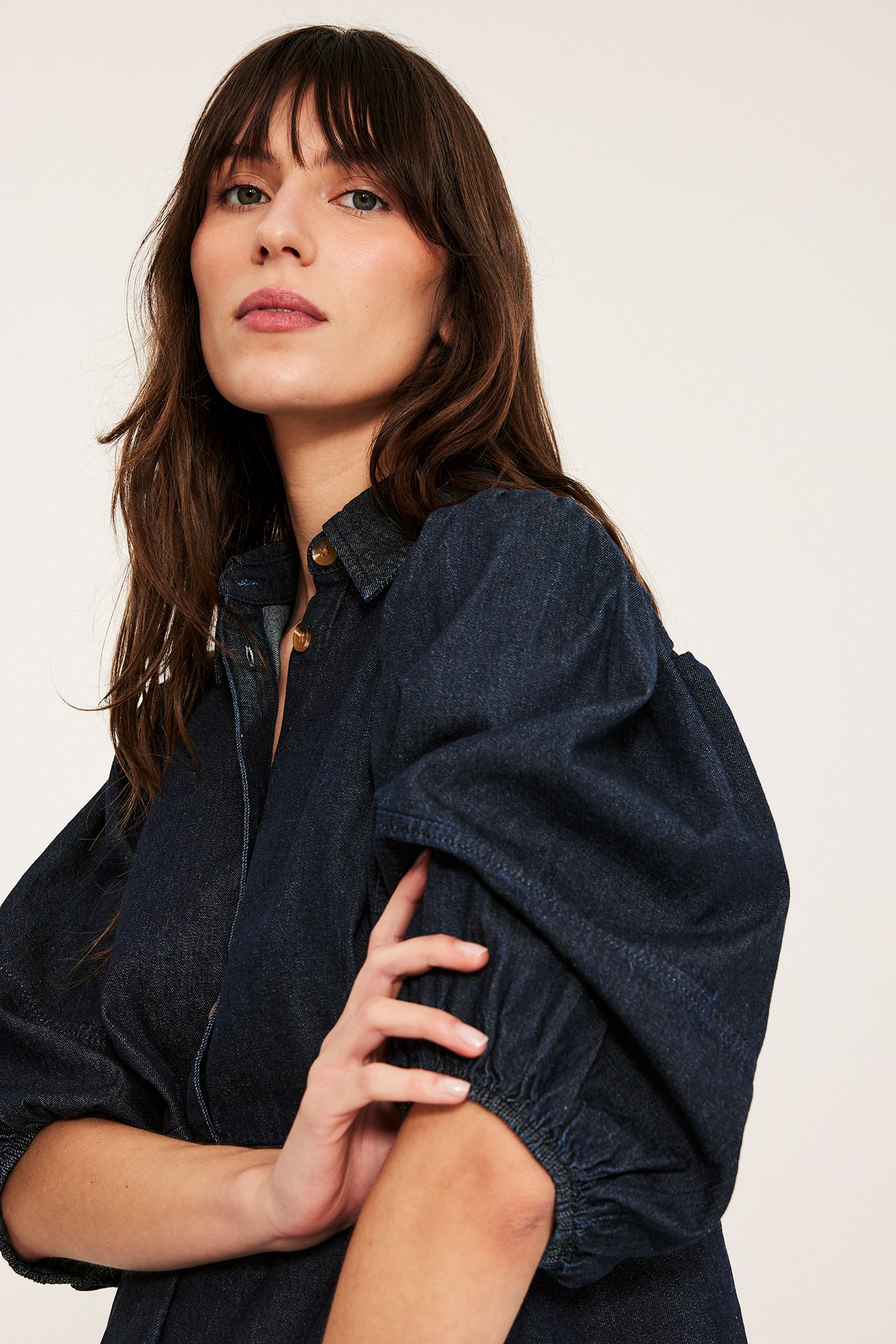 Zbliżenie na kobietę w ciemnoniebieskiej dżinsowej bluzce: kołnierz, bufiaste rękawy 3/4, guziki.