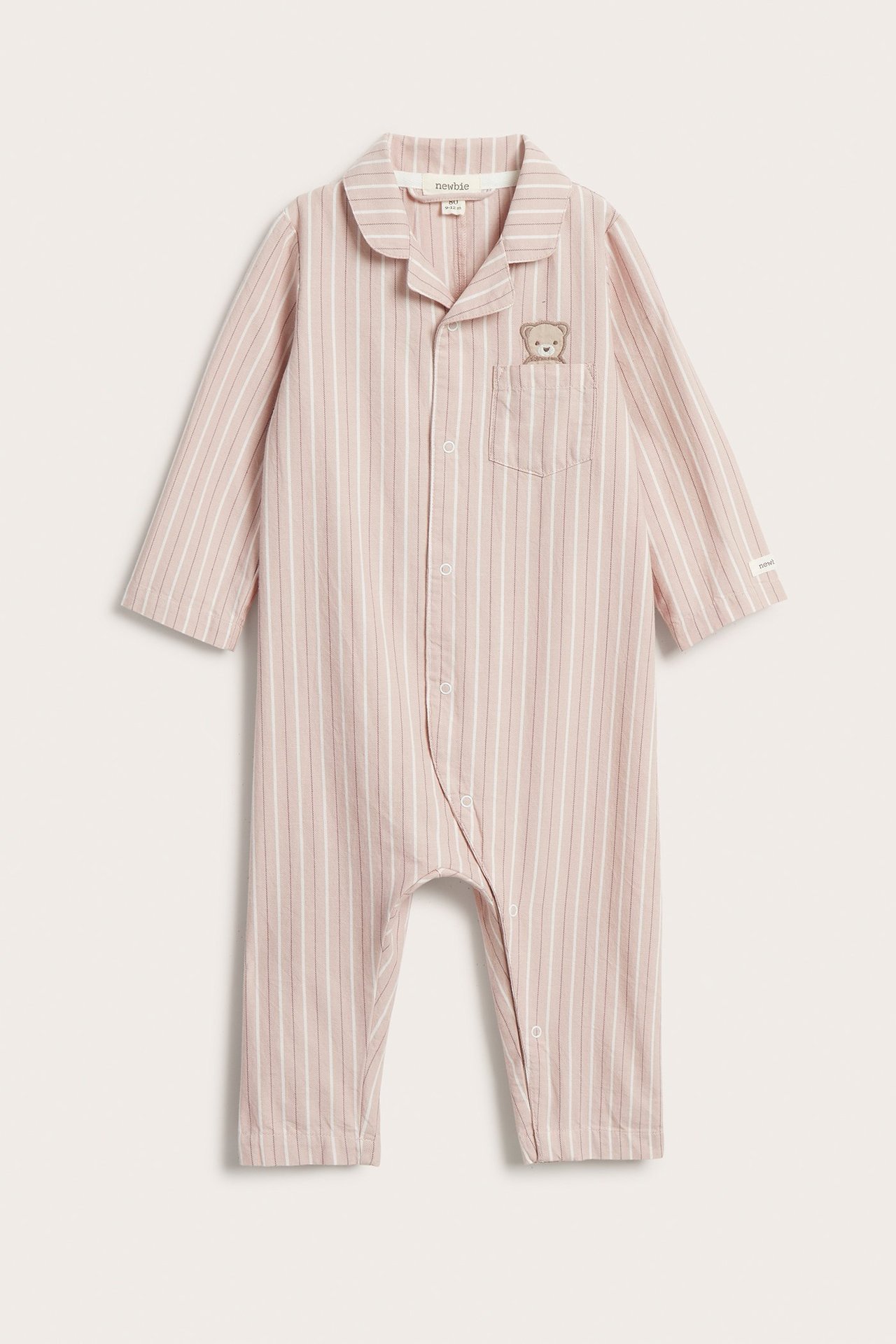 Front view: Vaaleanpunainen raidallinen vauvan pyjama, jossa rintataskussa brodeerattu nalle.