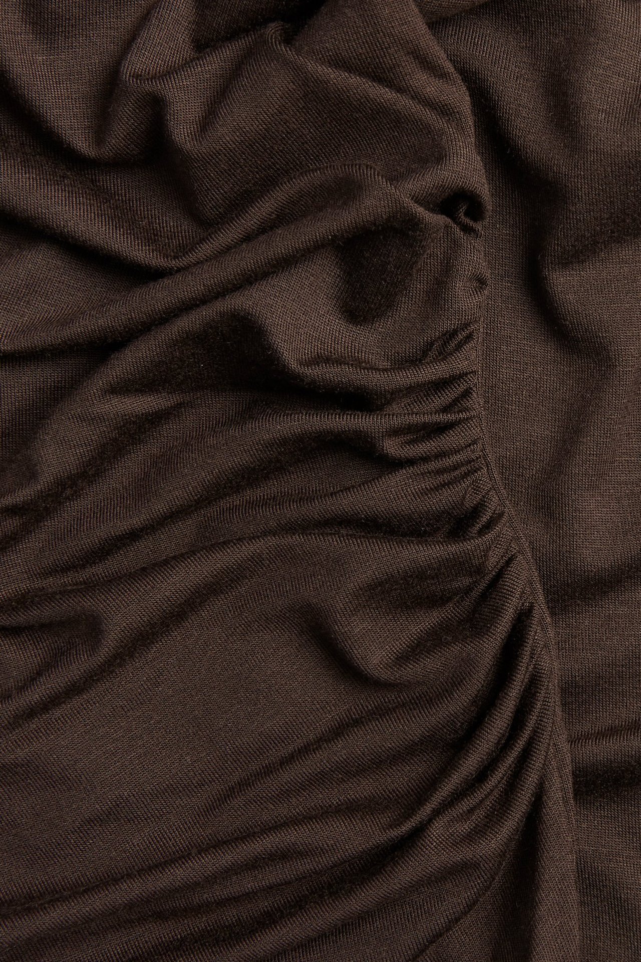 Zbliżenie na ciemnobrązowy, długi top z wiskozy z wyraźnym marszczeniem i drapowanym materiałem.