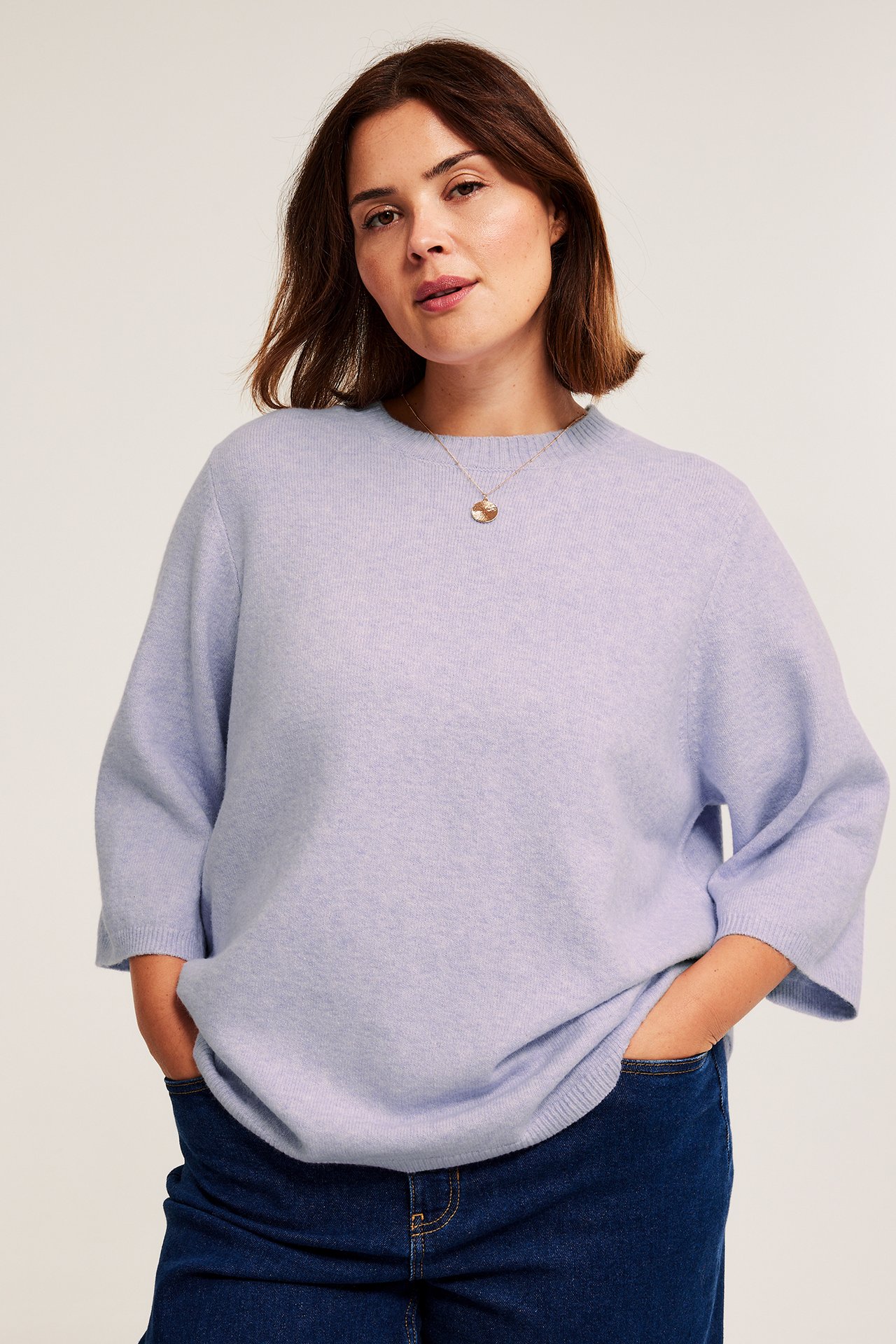 Etunäkymä: nainen yllään vaaleanlila meleerattu neulottu t-paita, 3/4 hihat, tummansiniset farkut, kultakaulakoru.