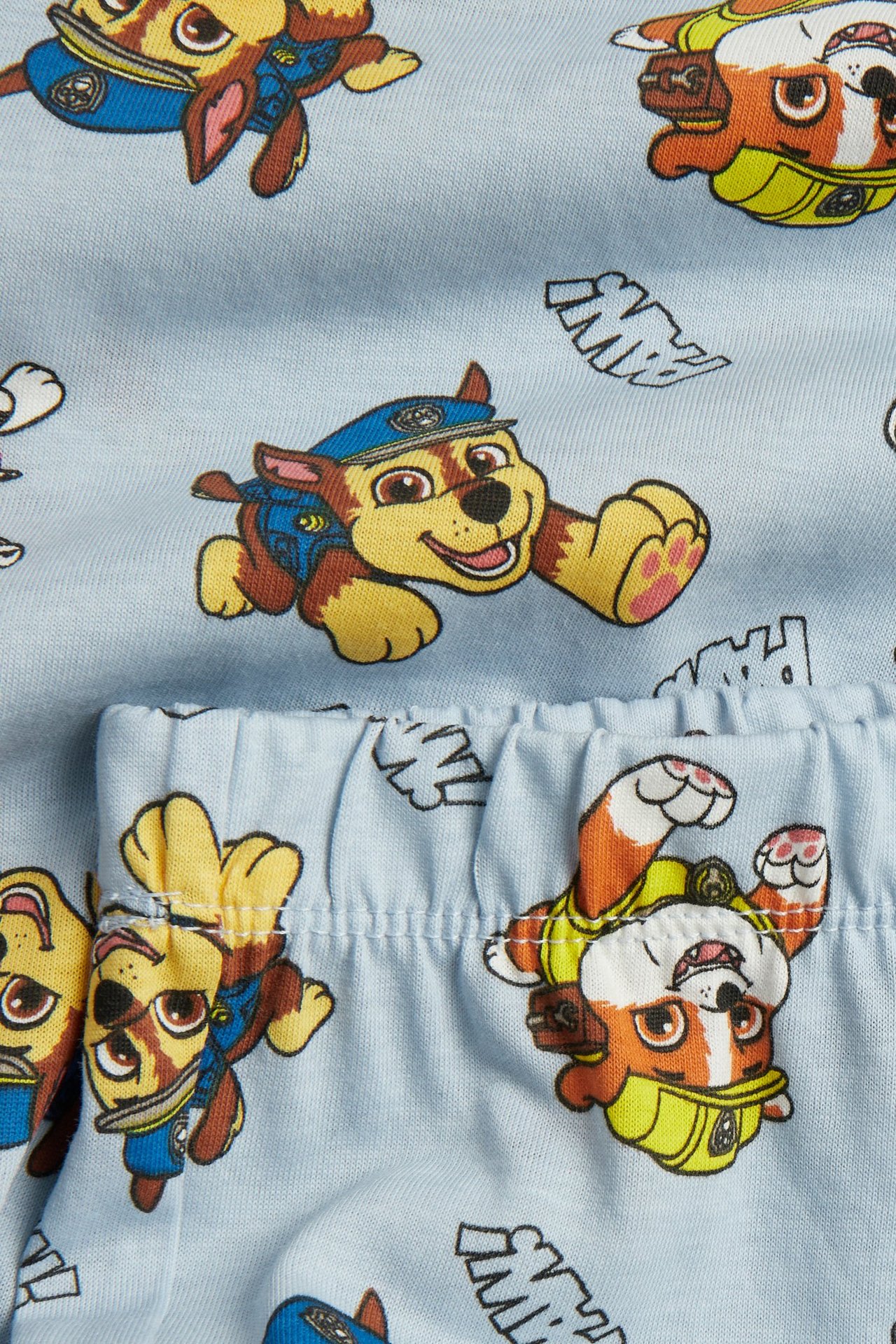 Zbliżenie na jasnoniebieską bawełnianą piżamę z nadrukiem Psiego Patrolu i elastyczną talią.