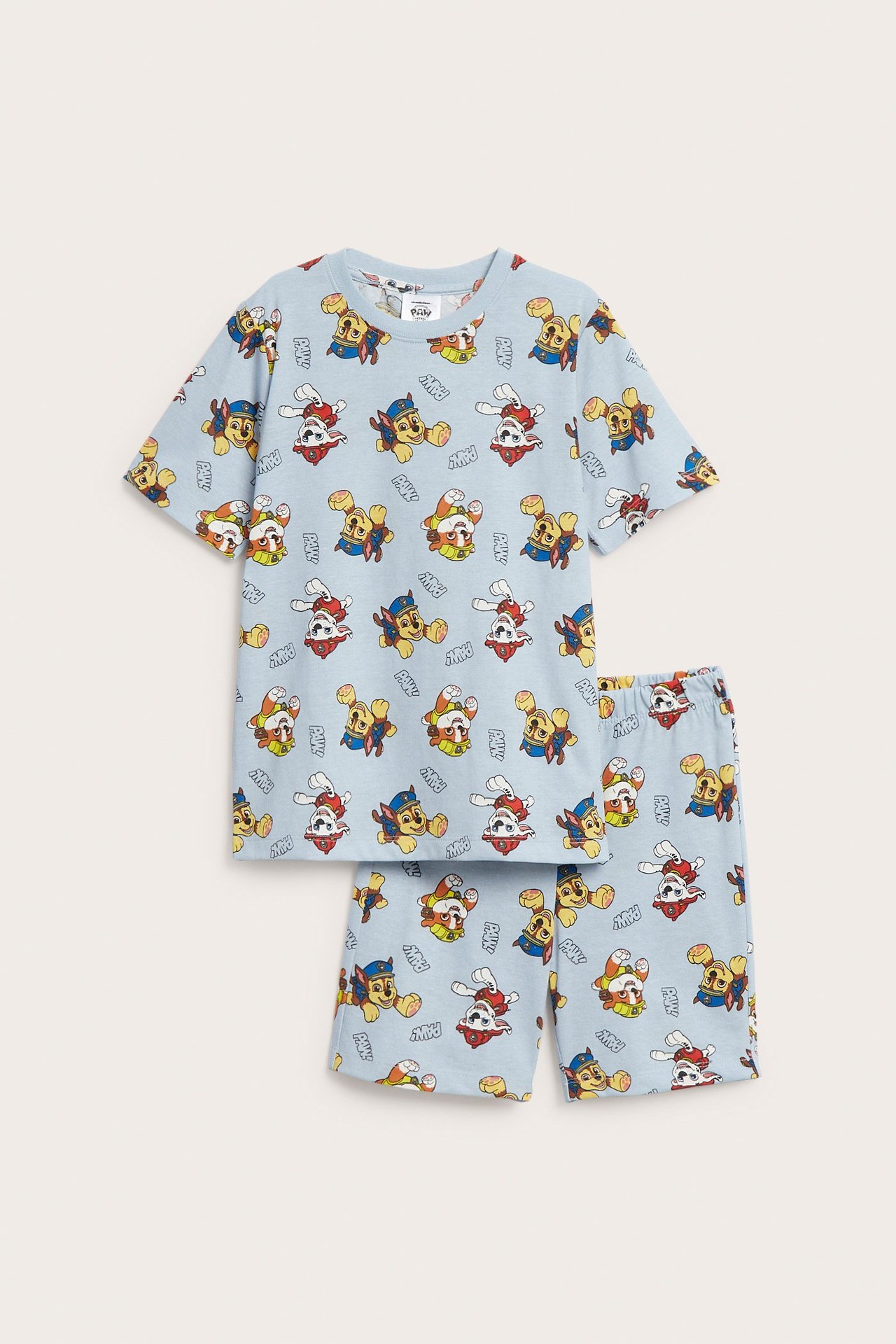 Widok z przodu dziecięcej, jasnoniebieskiej bawełnianej piżamy z krótkim rękawem, z nadrukiem Psiego Patrolu.