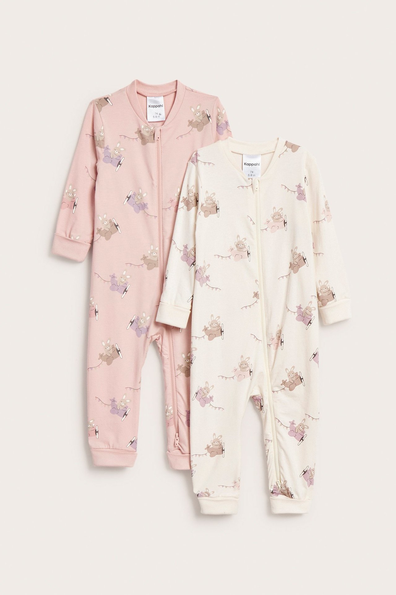 Edestä: kaksi vauvan unipukua, vaaleanpunainen ja luonnonvalkoinen, eläinkuviolla, kaksisuuntainen vetoketju.
