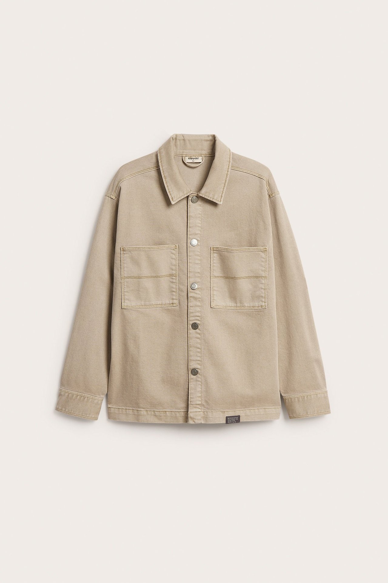 Framsida av en beige overshirt i bomullstwill med tryckknappar och två bröstfickor.