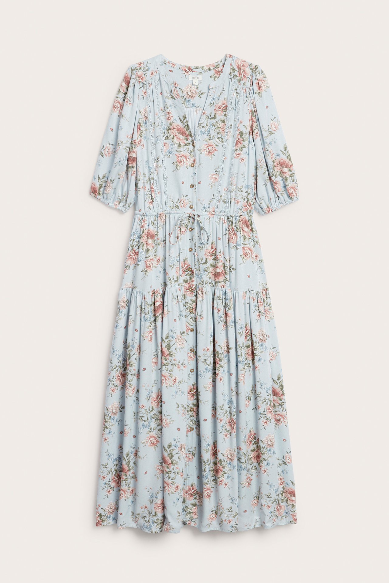 Frontbilde av en lyseblå blomstret viskosekjole med knapper, blonder, snøring i midjen og puffermer.
