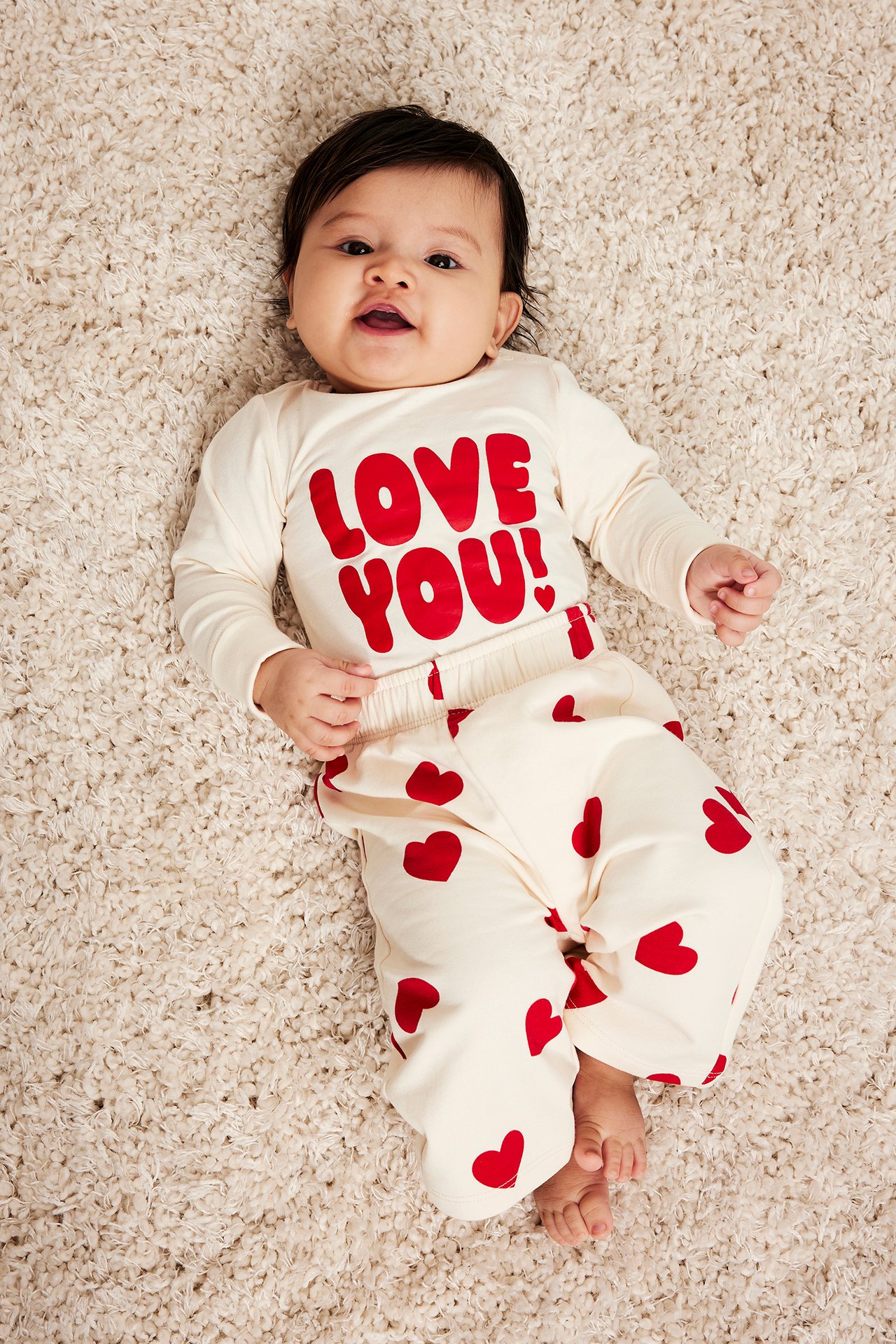 Topputsikt: baby i offwhite langermet body med rødt "LOVE YOU!"-trykk og matchende hjertebukse.