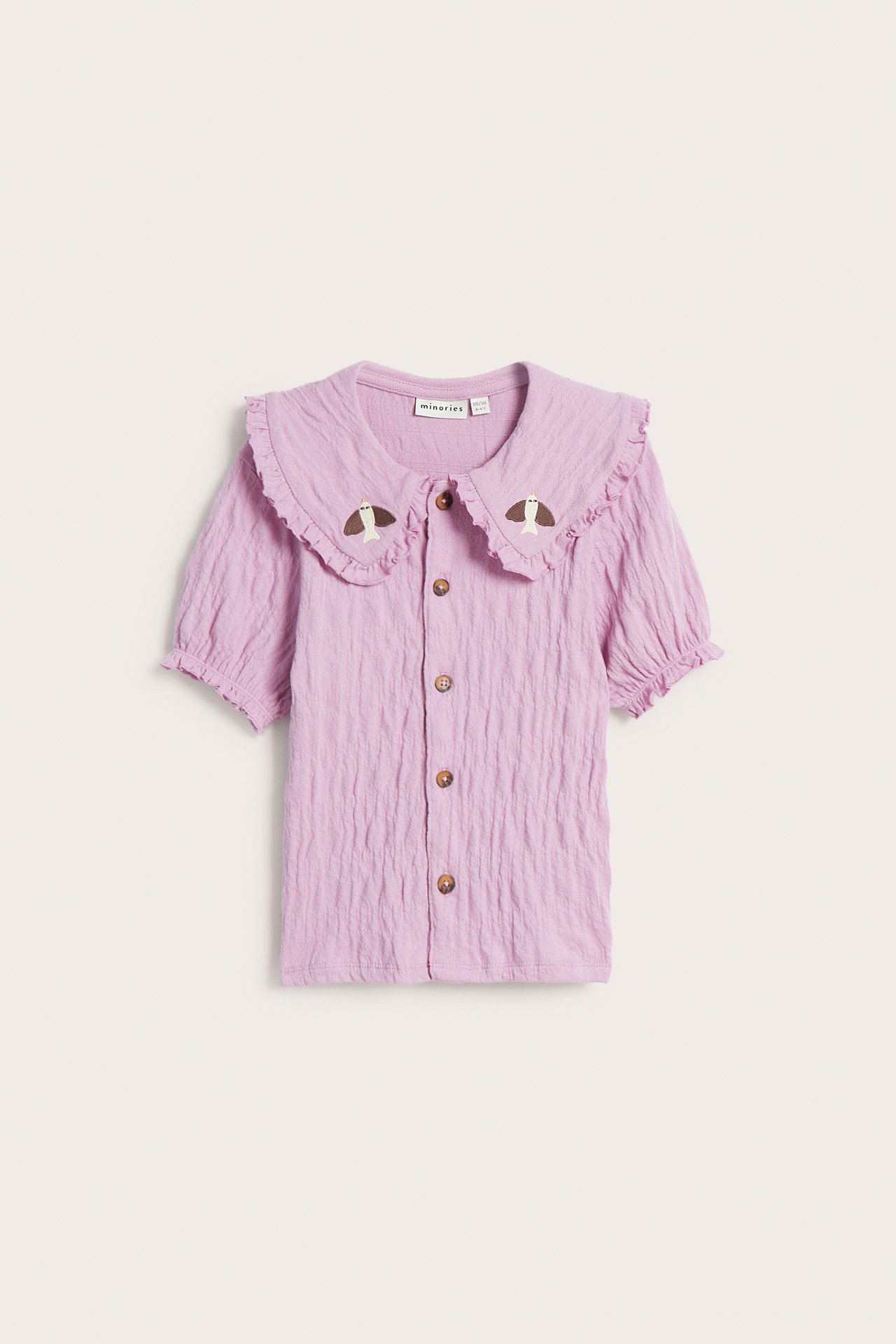 Framsida: Ljusrosa krinklad blus för barn med svampbroderad krage och knappar.