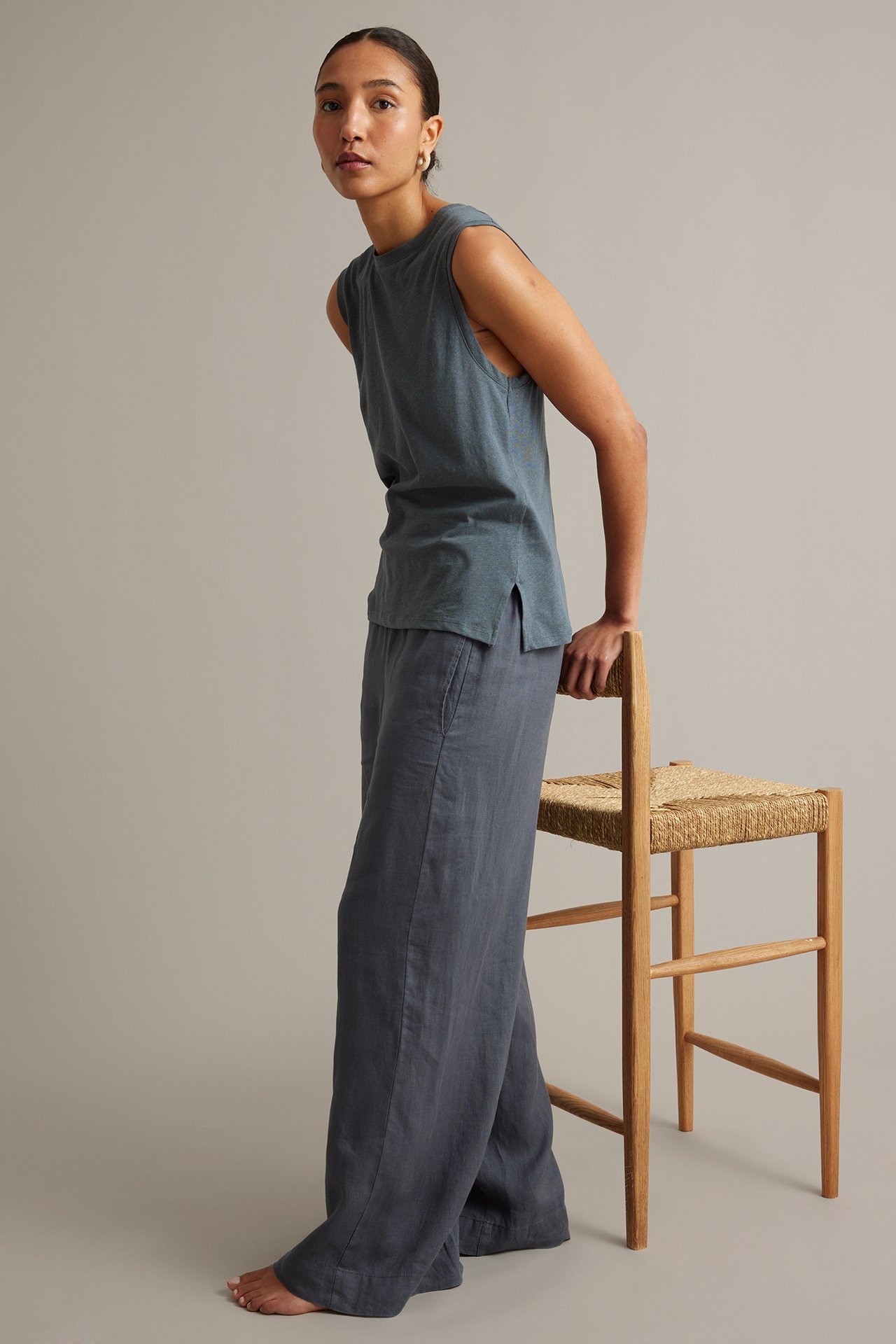 Sidebilde av kvinne i blått linblandingstopp med splitt og matchende vide bukser.