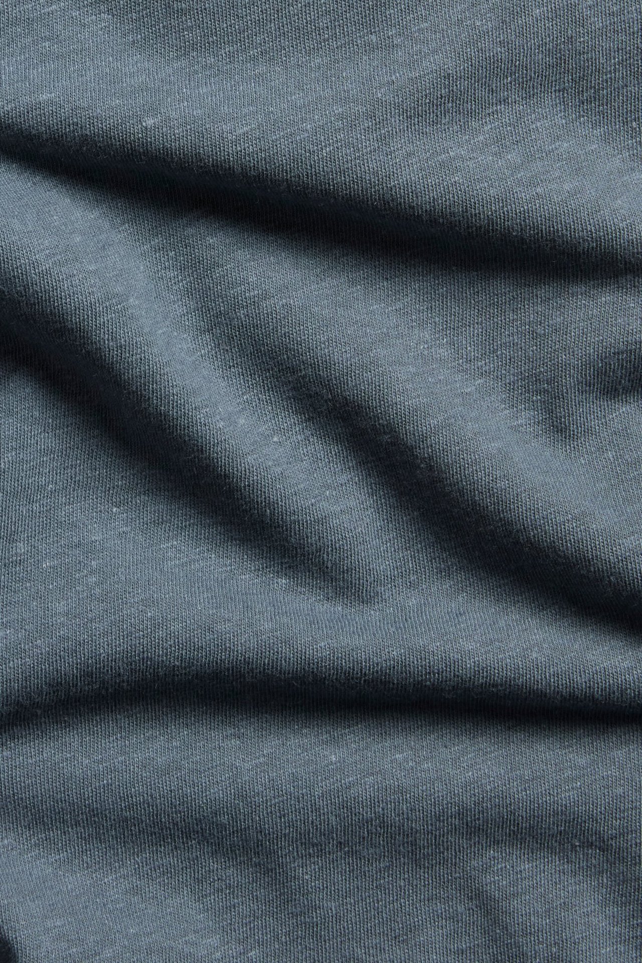 Zbliżenie na jednolity niebieski materiał z mieszanki lnu i bawełny, pokazujące jego teksturowaną powierzchnię.