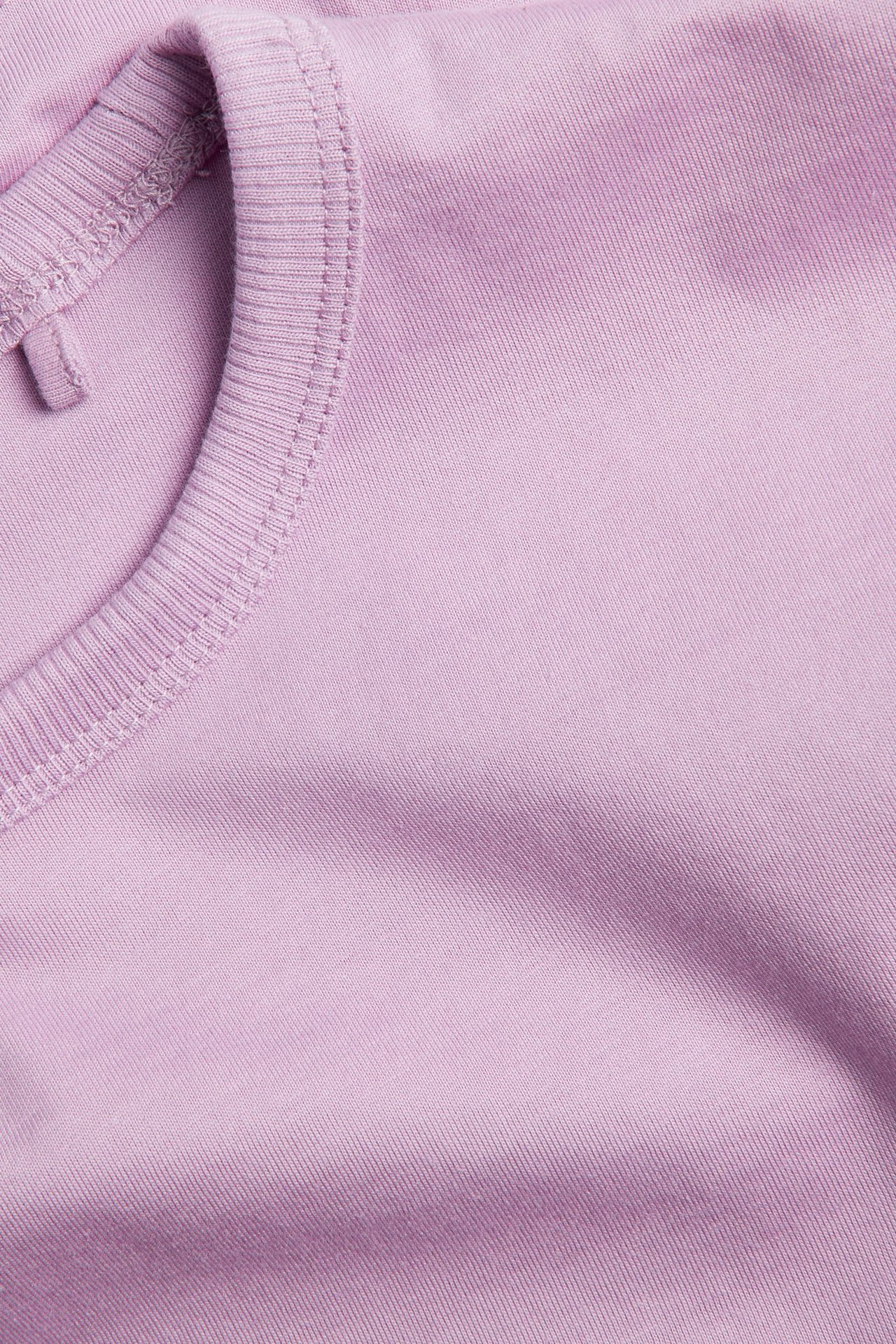 Zbliżenie na różowy bawełniany t-shirt z krótkimi rękawami i prążkowanym okrągłym dekoltem.