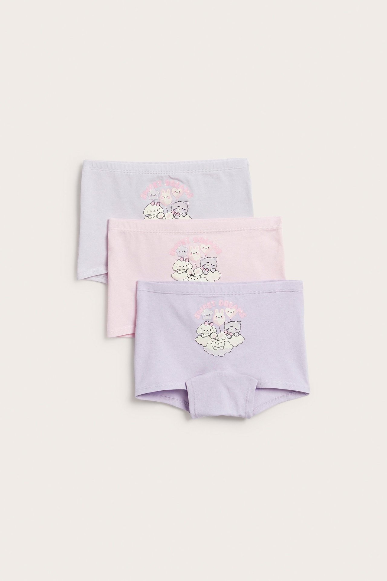 Widok z przodu trzech bokserek dziecięcych: jasnoliliowych, jasnoróżowych i jasnoliliowych, wszystkie z nadrukiem kreskówkowym.