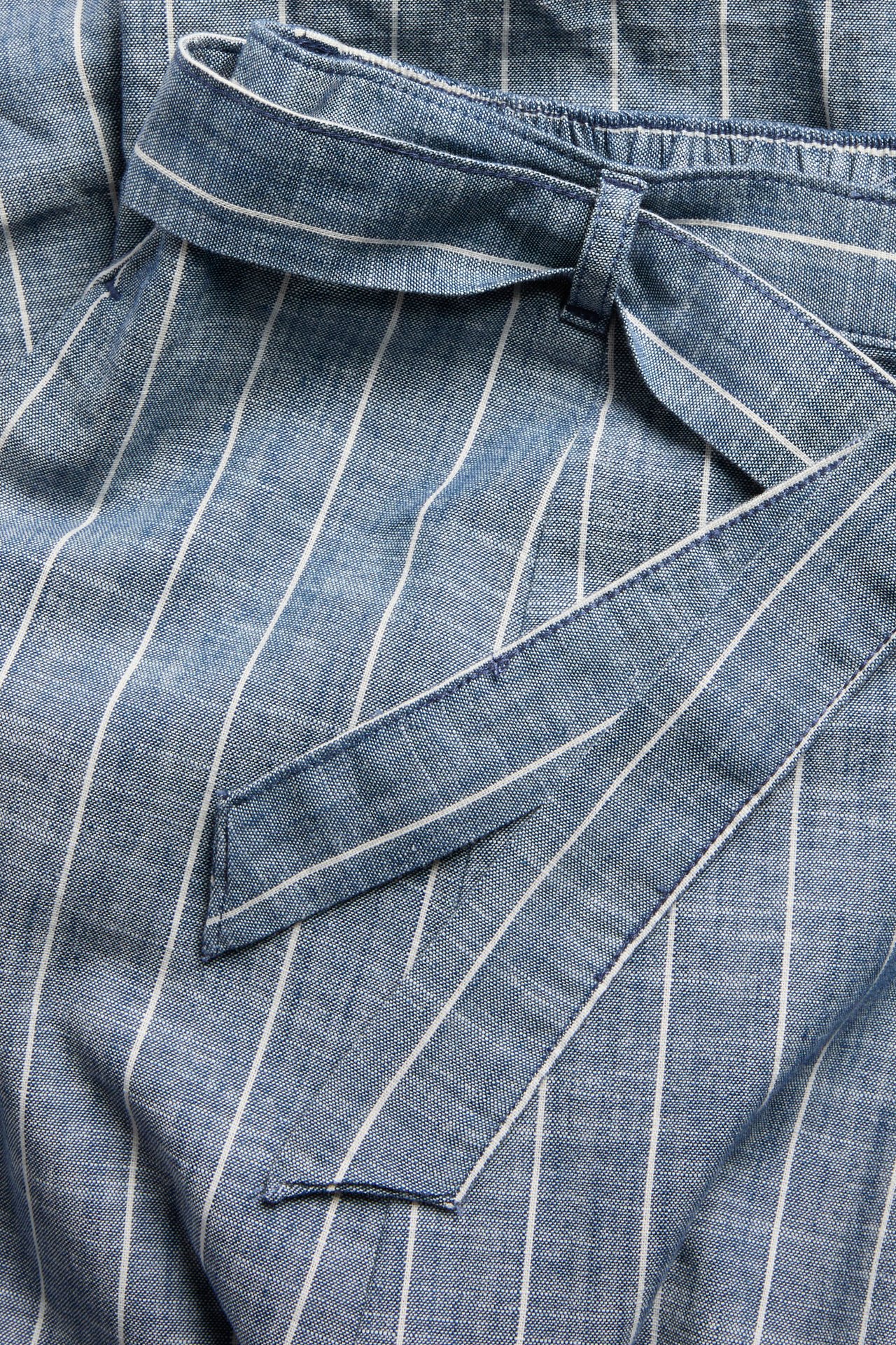 Zbliżenie: niebiesko-biała spódnica w paski, bawełniana, z elastyczną talią, wiązanym paskiem i kieszenią.