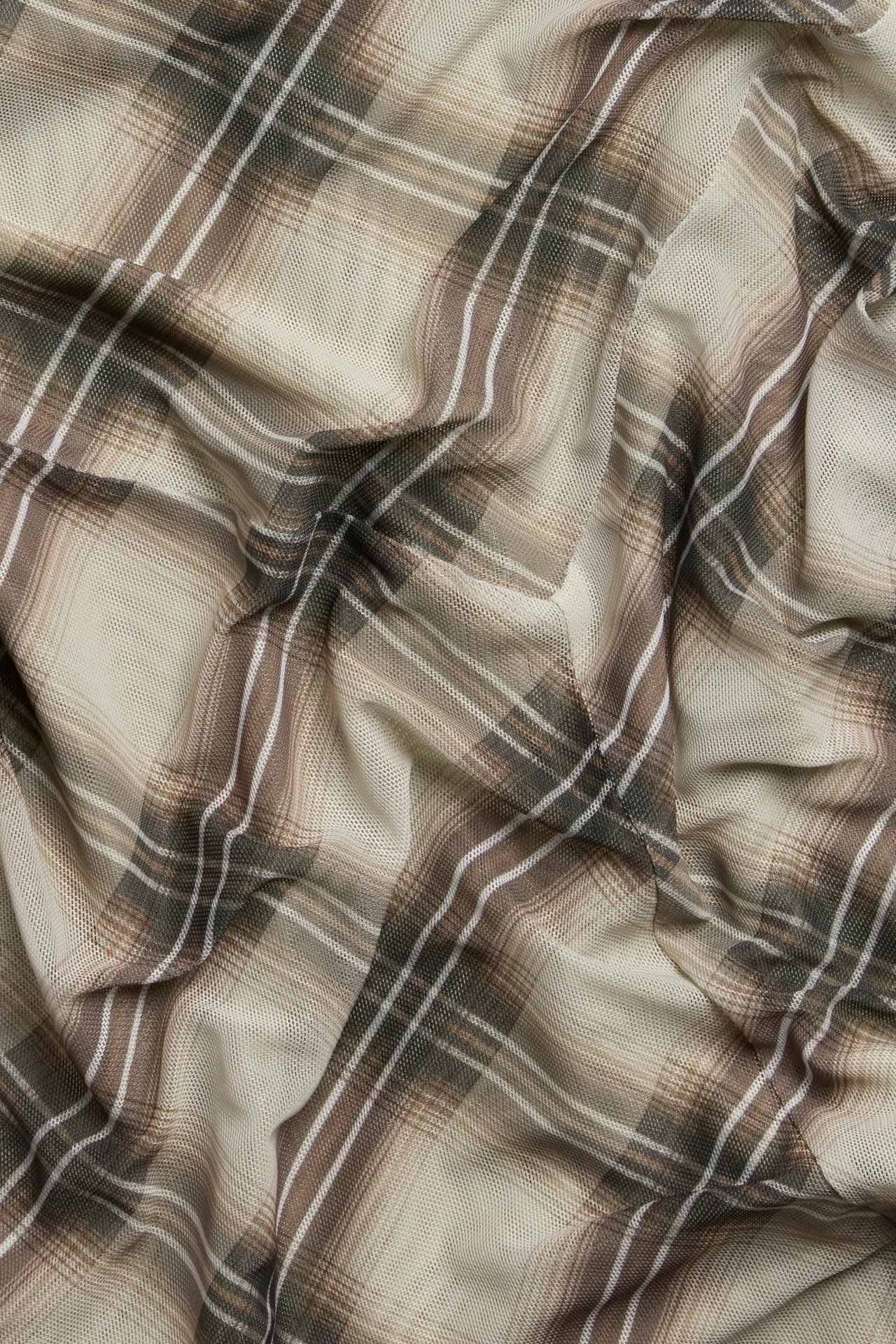 Zbliżenie beżowej tkaniny siatkowej z brązowo-białym wzorem w kratę, pofałdowanej.