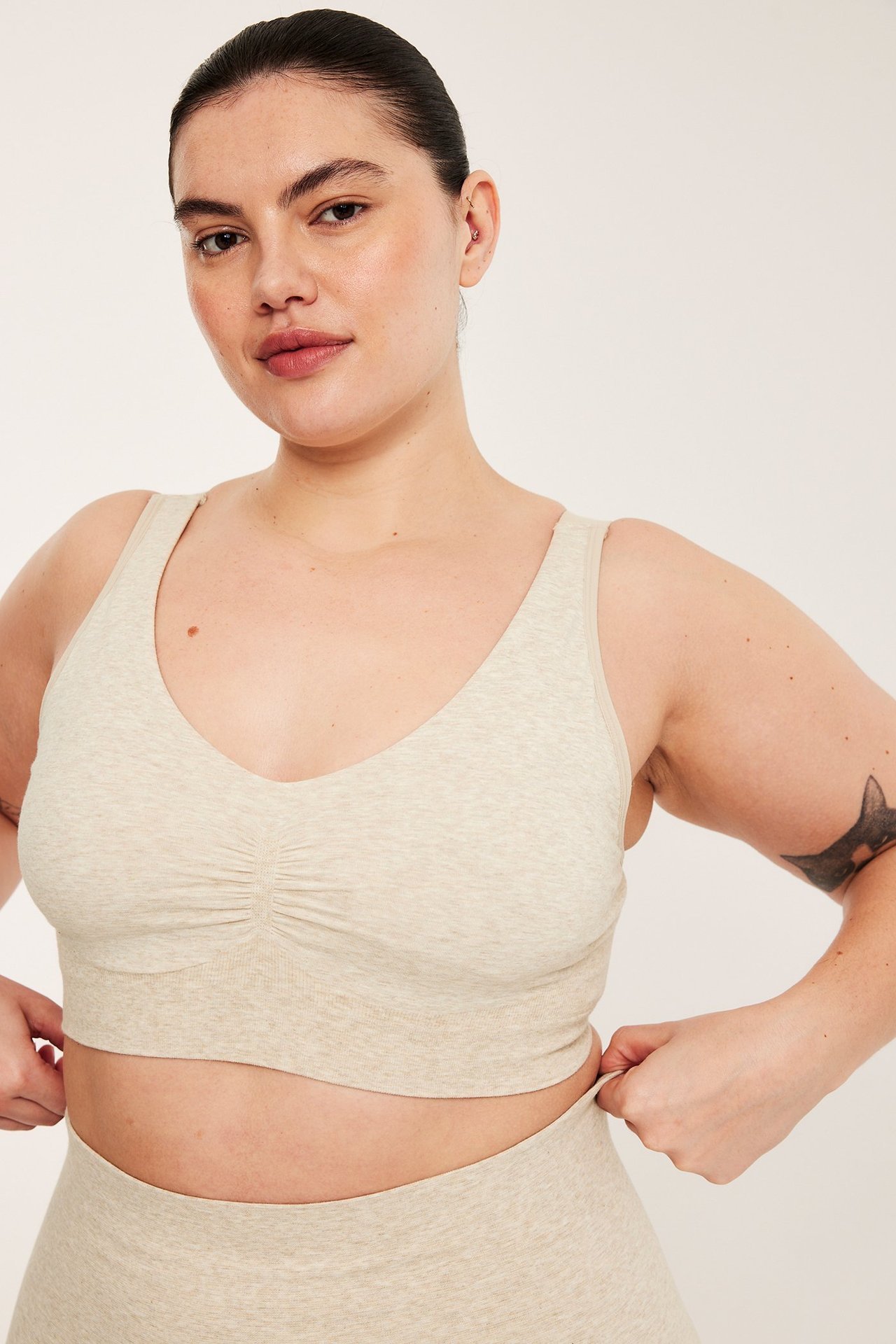 Framifrån, kvinna i beige melerad sömlös bh med rynkad detalj och matchande underdel.