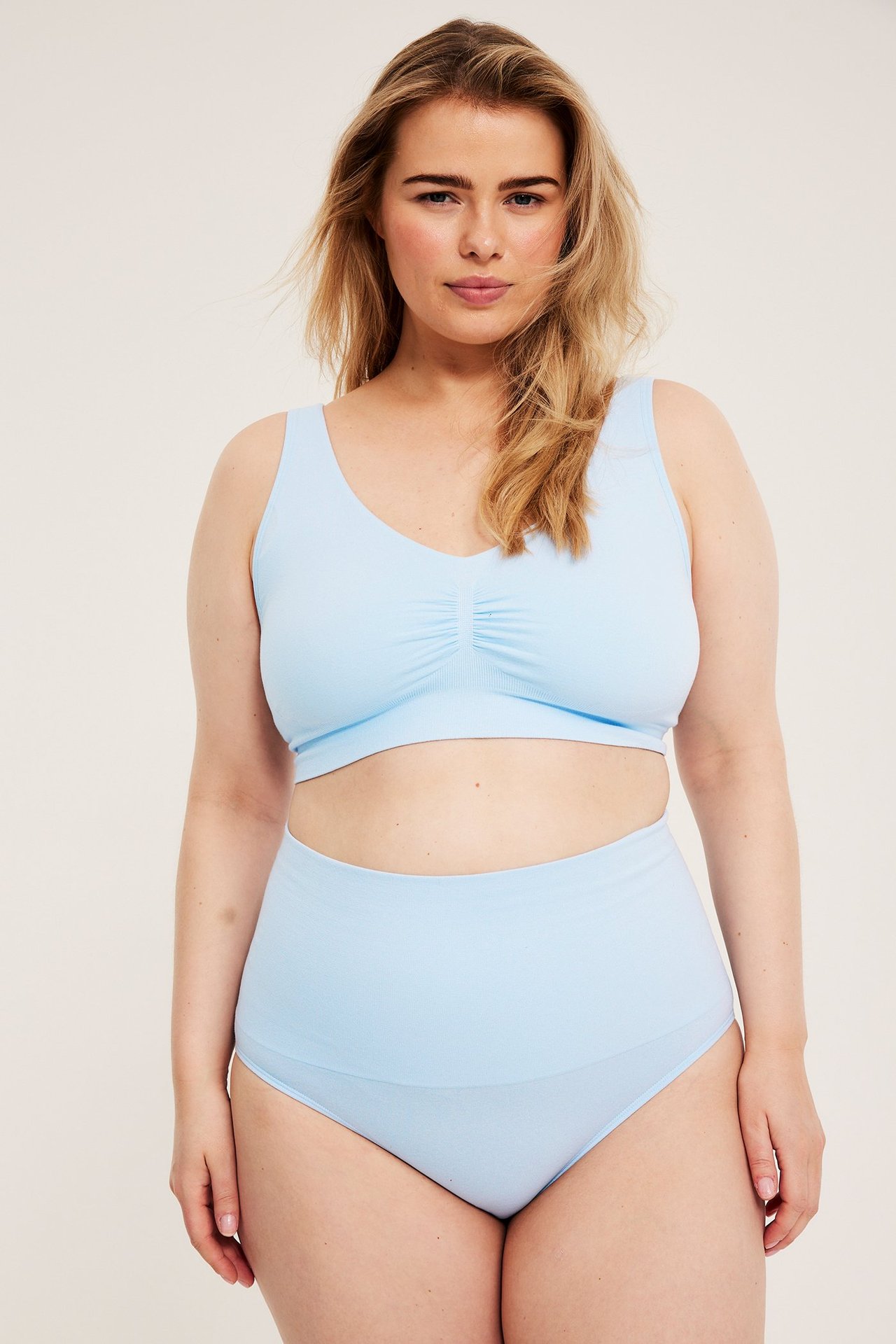 Frontvisning: Kvinne i lyseblå sømløs BH med brede stropper og matchende truser med høyt liv.