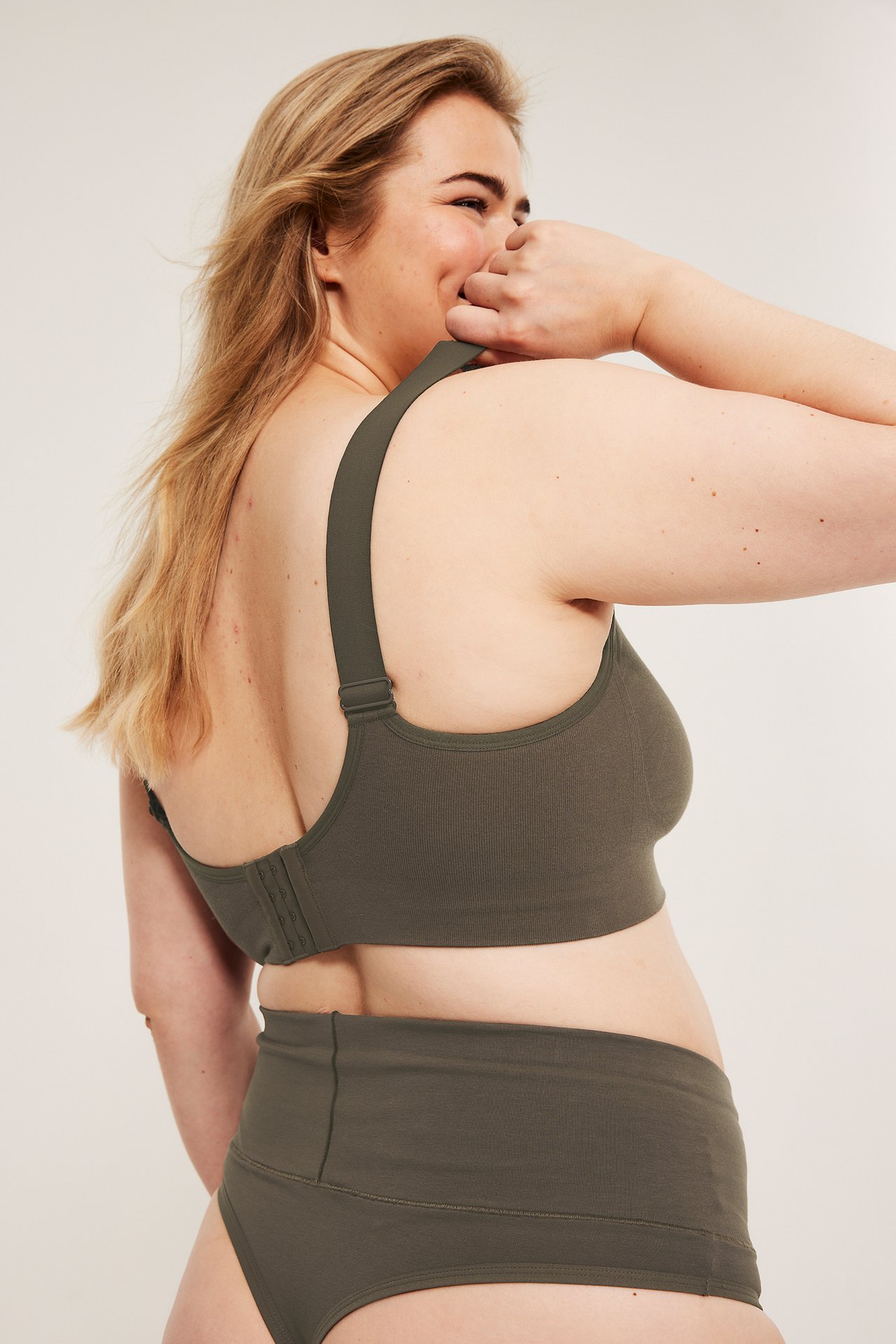 Sideutsikt av kvinne i mørkebrun sømløs ribbet BH med brede stropper og matchende høytlivstruser.