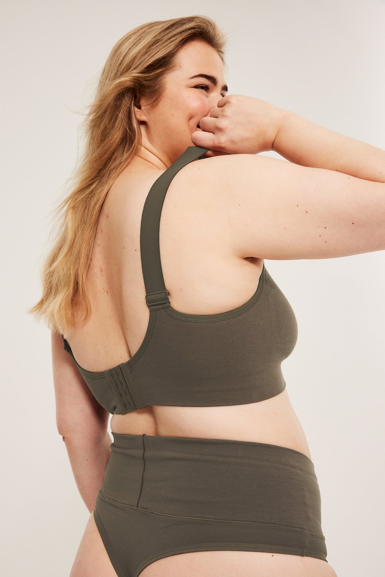 Sideutsikt av kvinne i mørkebrun sømløs ribbet BH med brede stropper og matchende høytlivstruser.