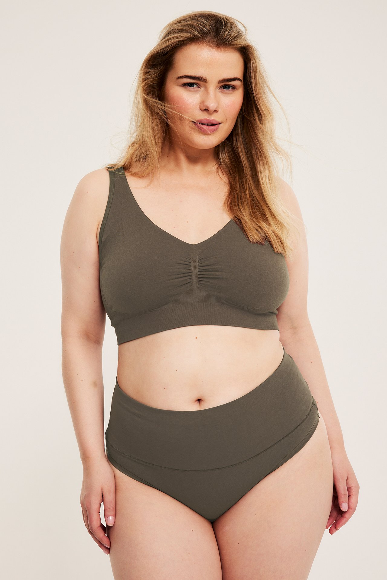 Front, kvinne har på seg en mørkebrun sømløs bomullsbh med brede stropper og matchende truser.