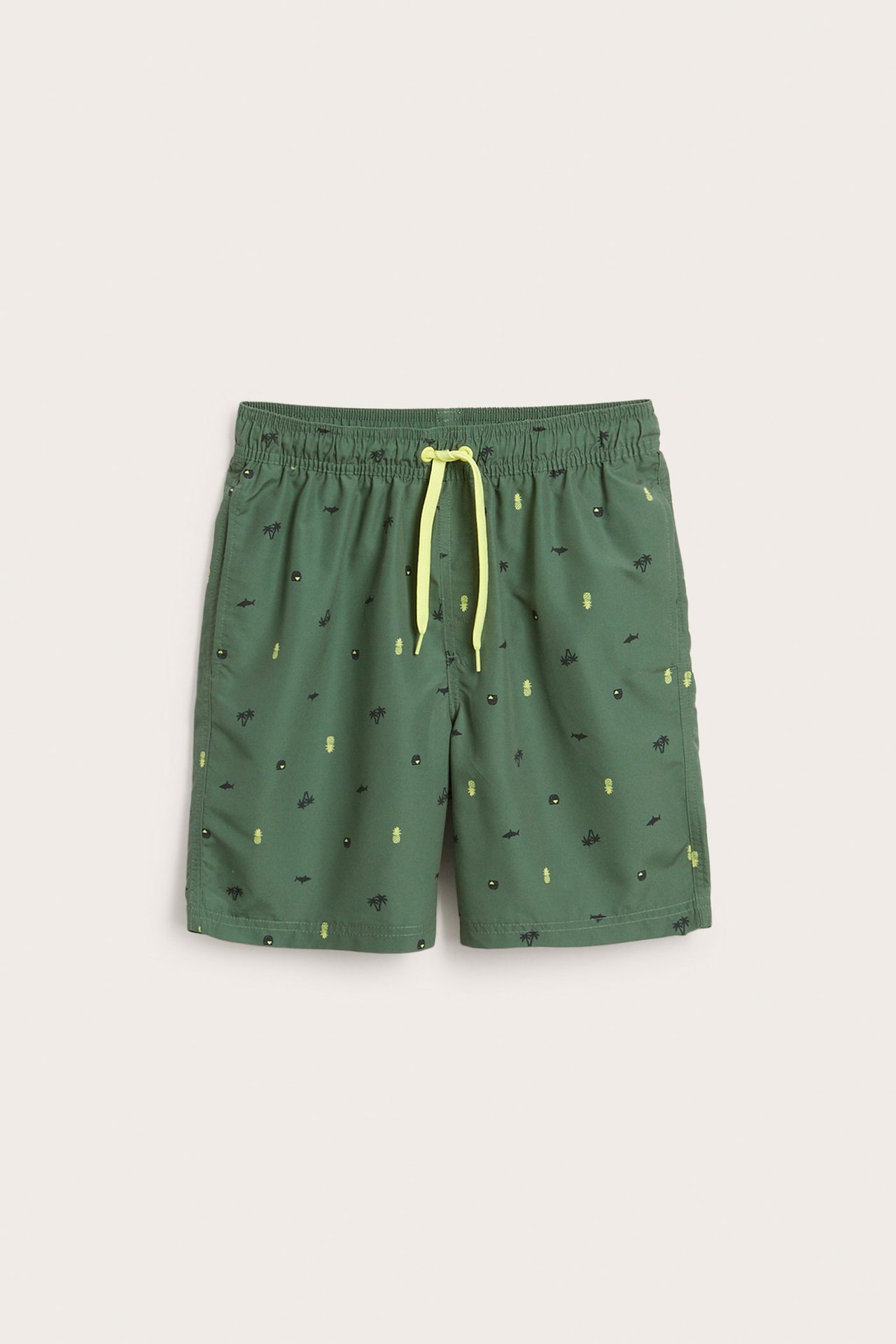 Frontvisning av grønne mønstrede badeshorts for barn med gul snøring og elastisk linning.