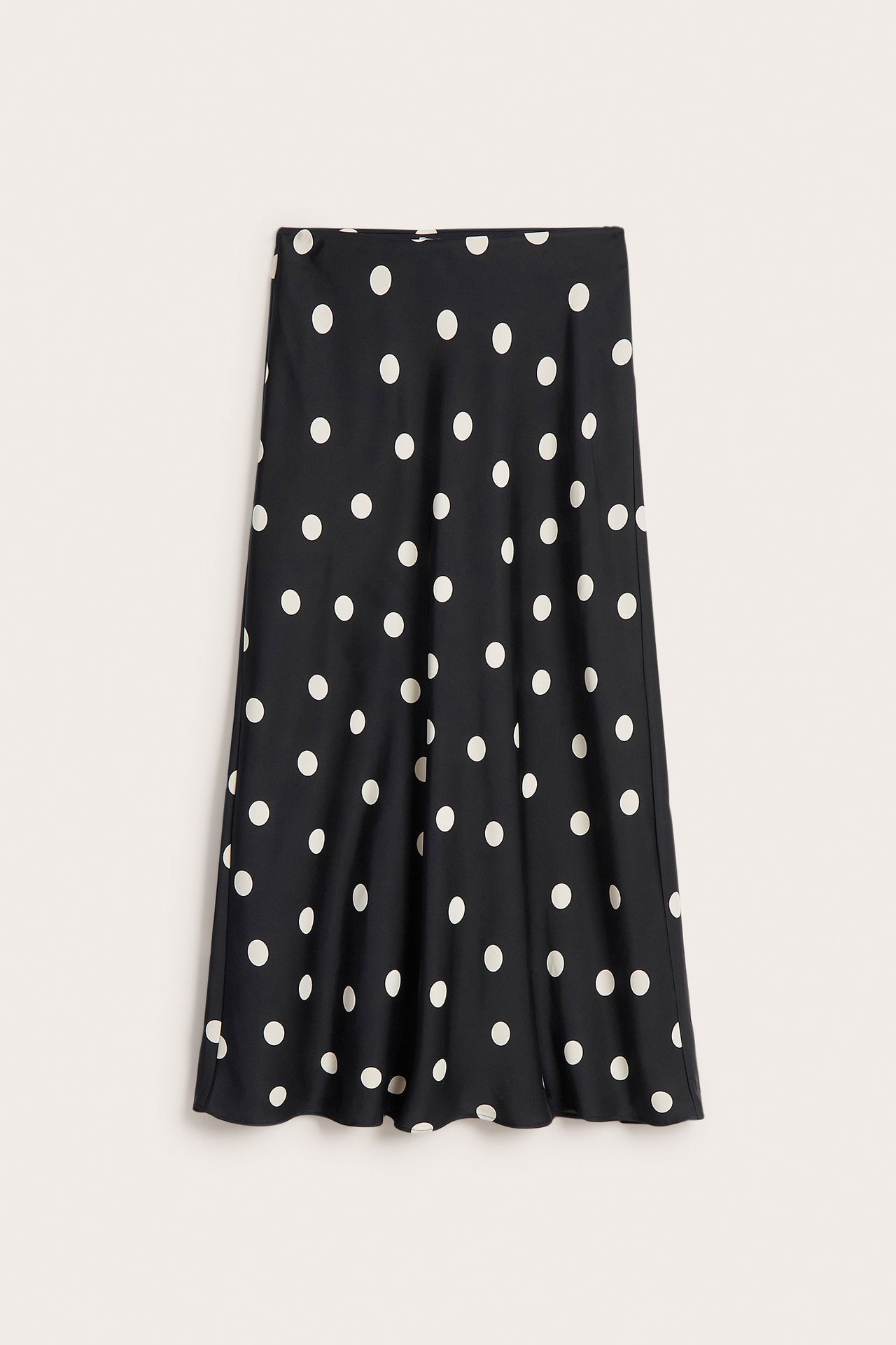 Forfra: svart prikkete satengskjørt, med lett utsvingt A-linje i midilengde.