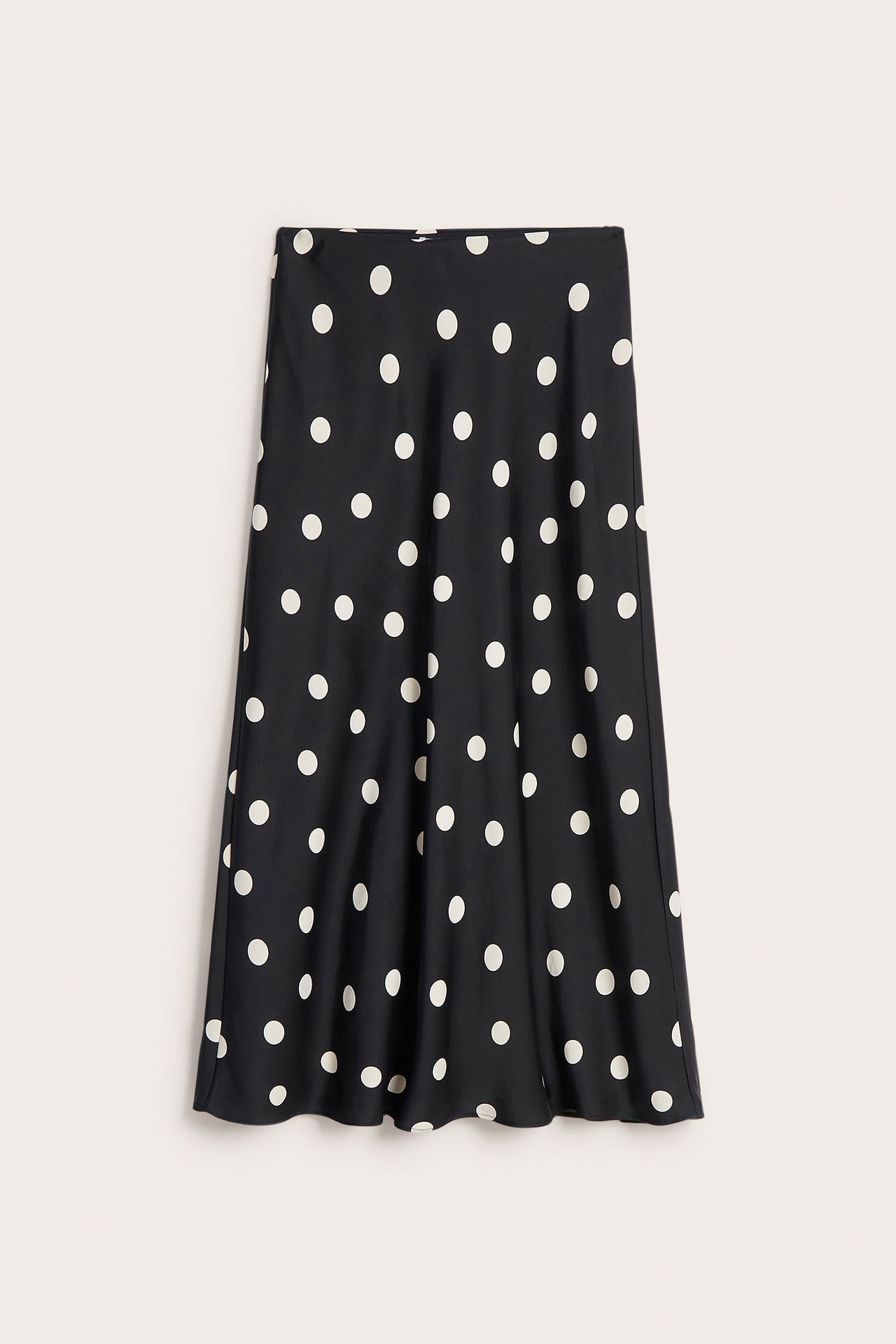 Forfra: svart prikkete satengskjørt, med lett utsvingt A-linje i midilengde.