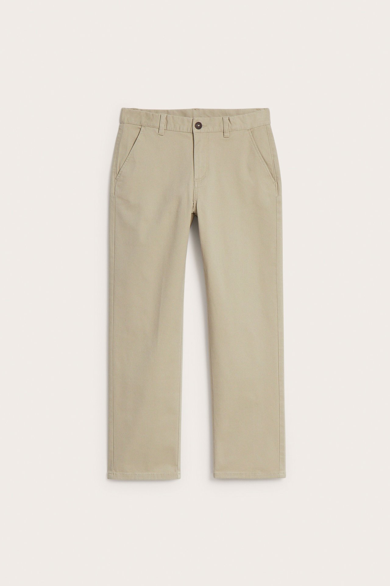 Edestä: beigenväriset, yksiväriset lasten chinot pehmeää joustavaa puuvillaa, napilla ja sepaluksella.