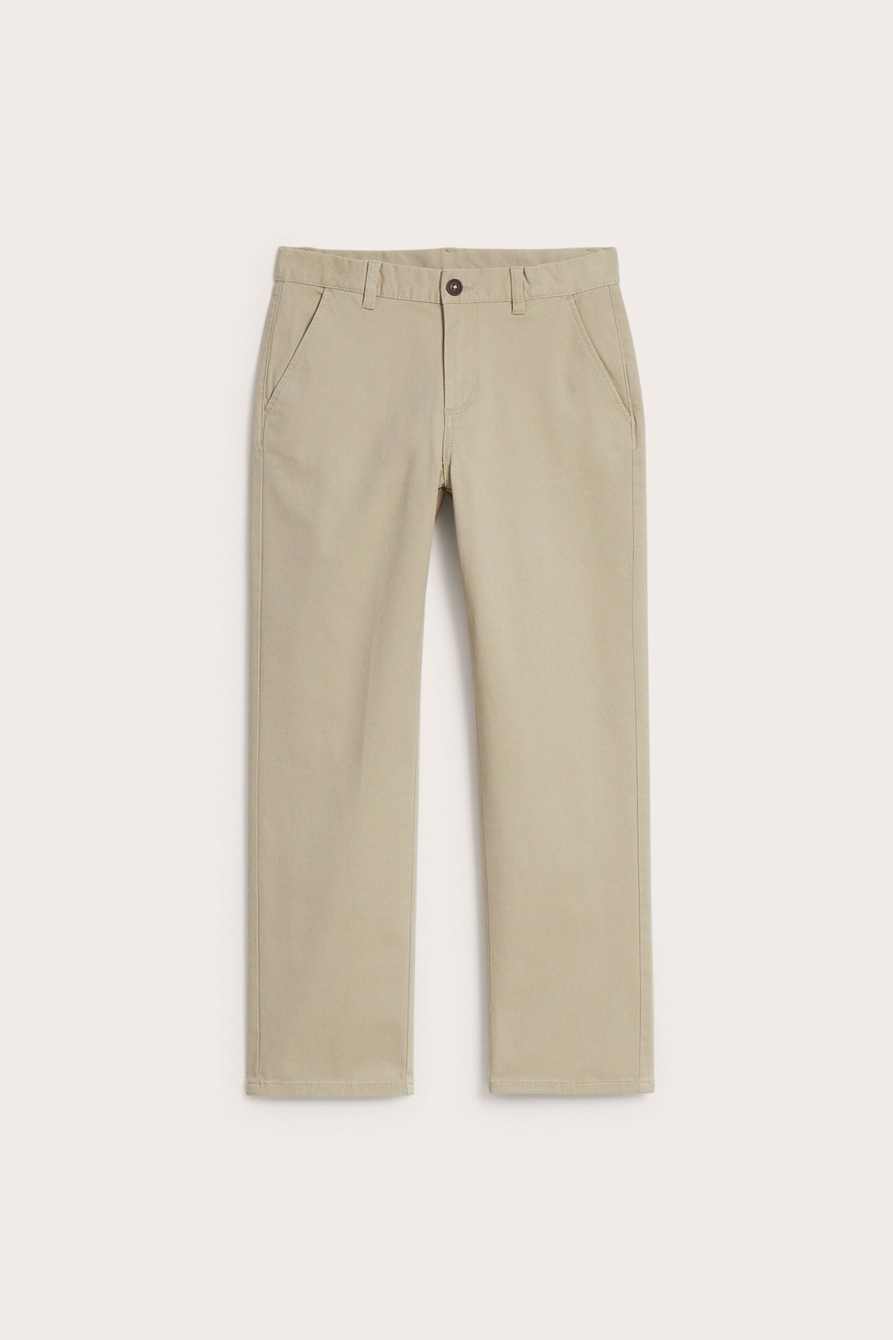 Edestä: beigenväriset, yksiväriset lasten chinot pehmeää joustavaa puuvillaa, napilla ja sepaluksella.