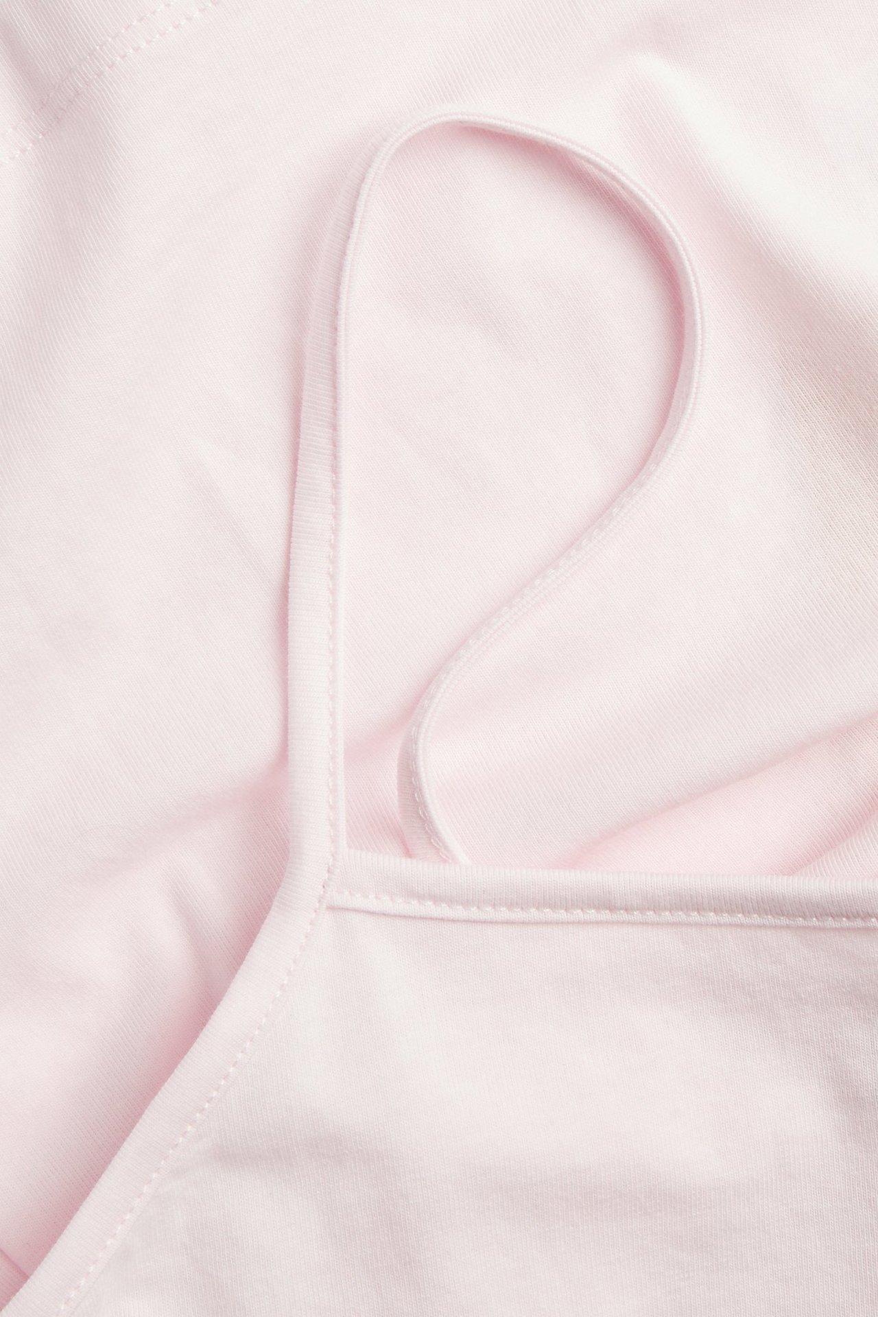 Widok z bliska, z góry, jasnoróżowej koszulki bawełnianej na cienkich ramiączkach.