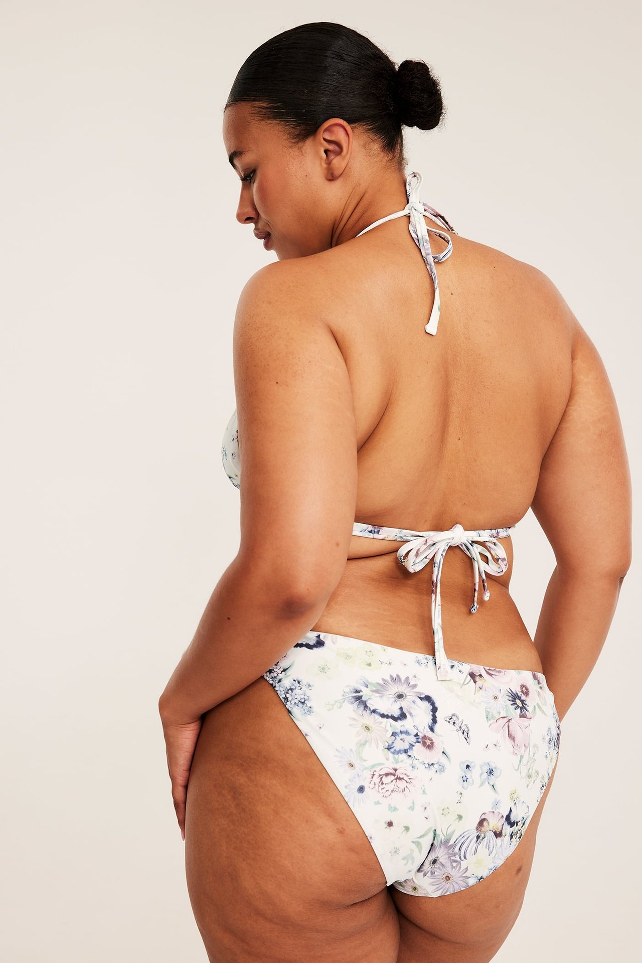 Kvinna bakifrån i vit blommig bikinitopp och matchande trosa.