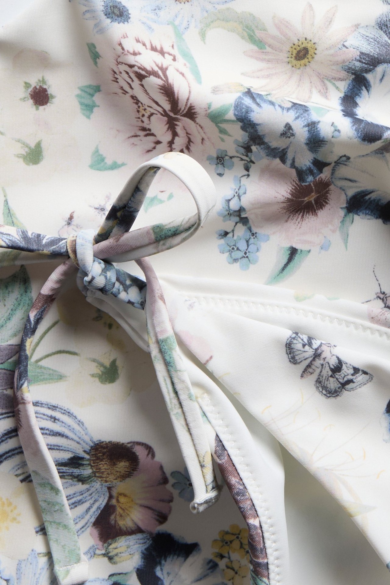 Nærbilde av en offwhite mønstret bikinitruse med knytebånd.