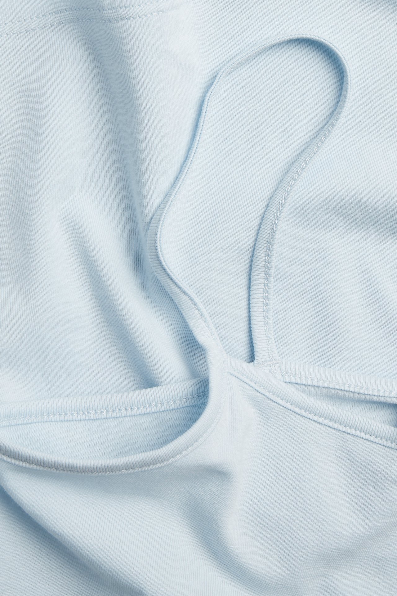 Närbild av ett ljusblått bomullsbaslinne med smala axelband.