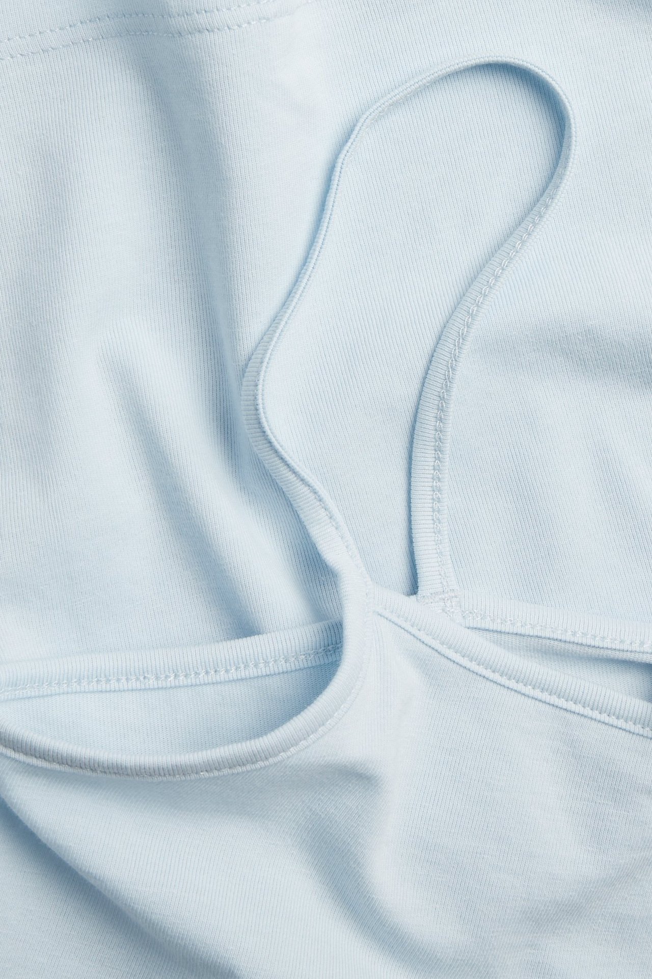 Zbliżenie na jasnoniebieski bawełniany top na ramiączkach, z cienkimi paskami.