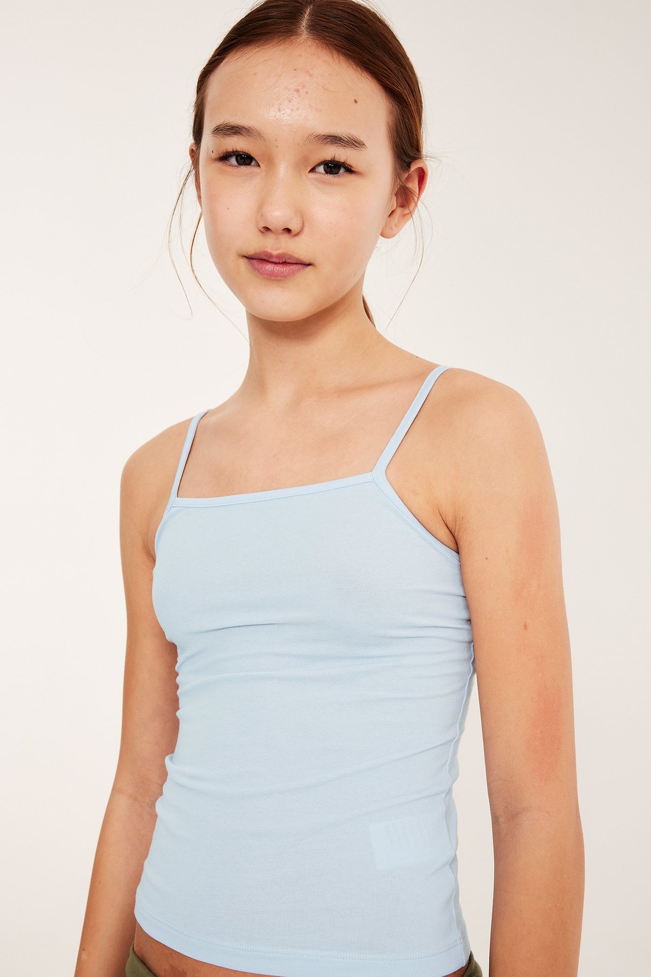 Widok z przodu dziecka w jasnoniebieskim, dopasowanym topie na ramiączkach.