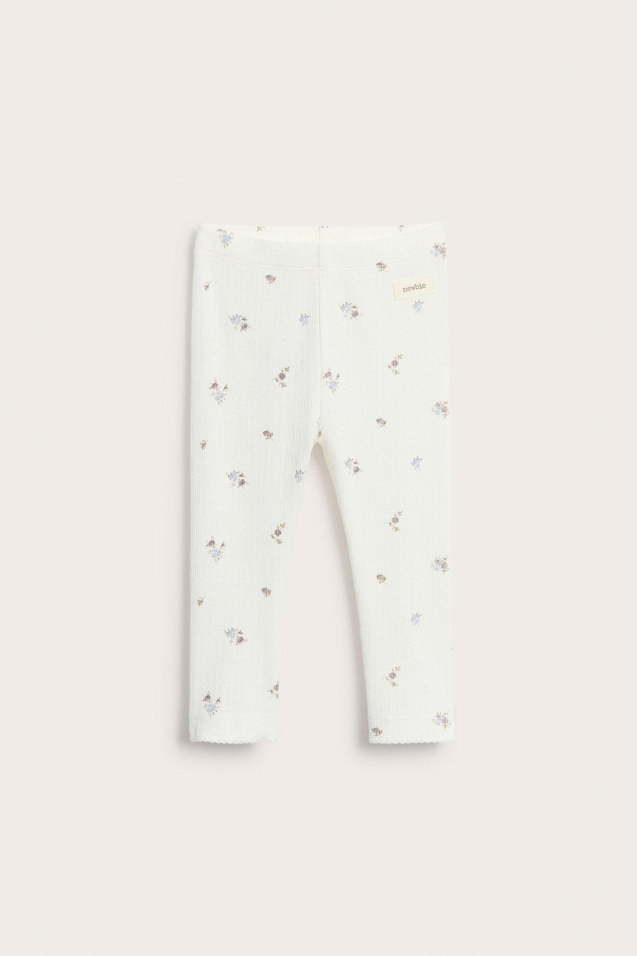 Frontvisning av offwhite ribbestrikkede leggings med blomstermønster og picotkant i benåpningen.