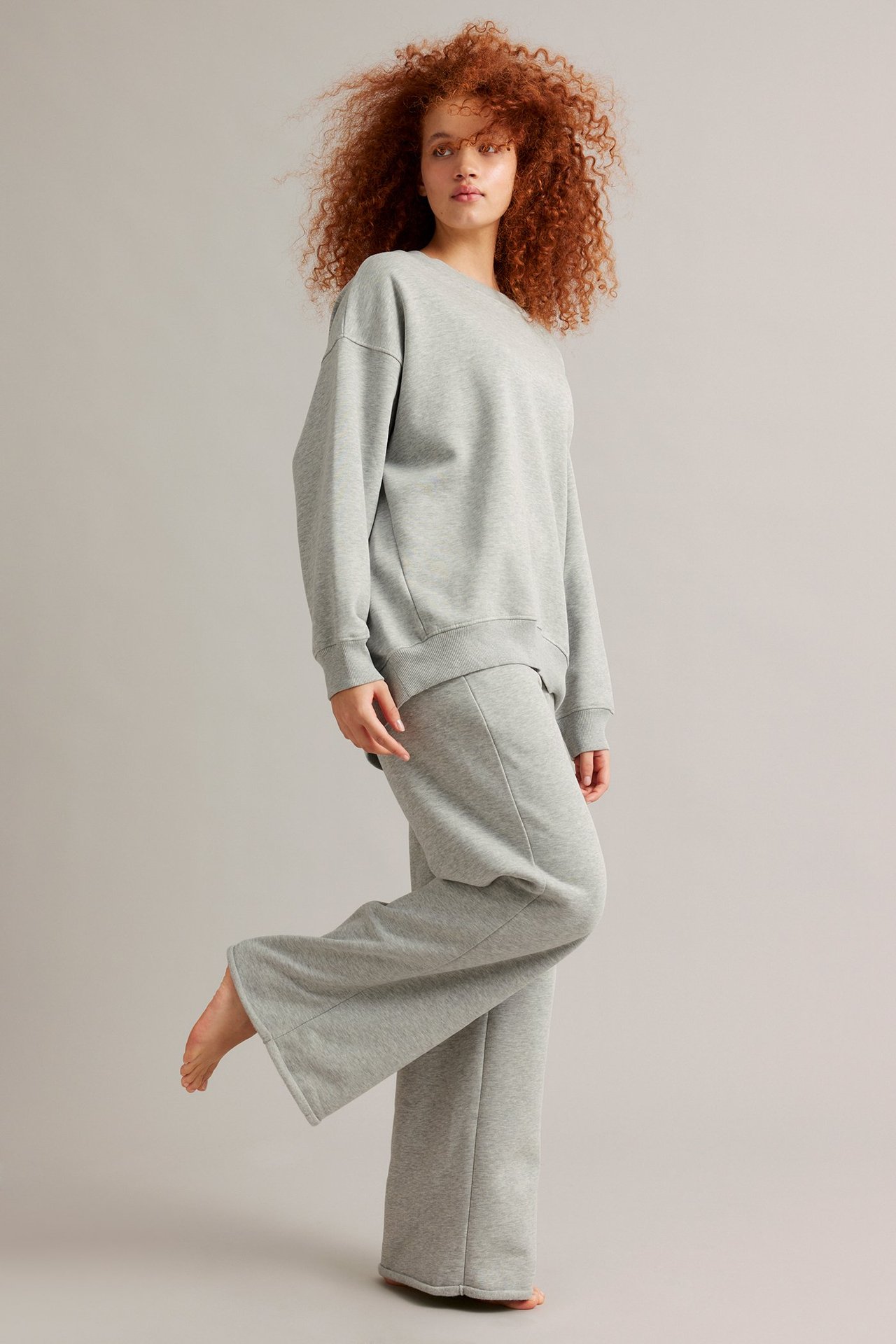 Edestä, nainen yllään vaaleanharmaameleeratut suorat collegehousut joustovyötäröllä ja yhteensopiva collegepaita.