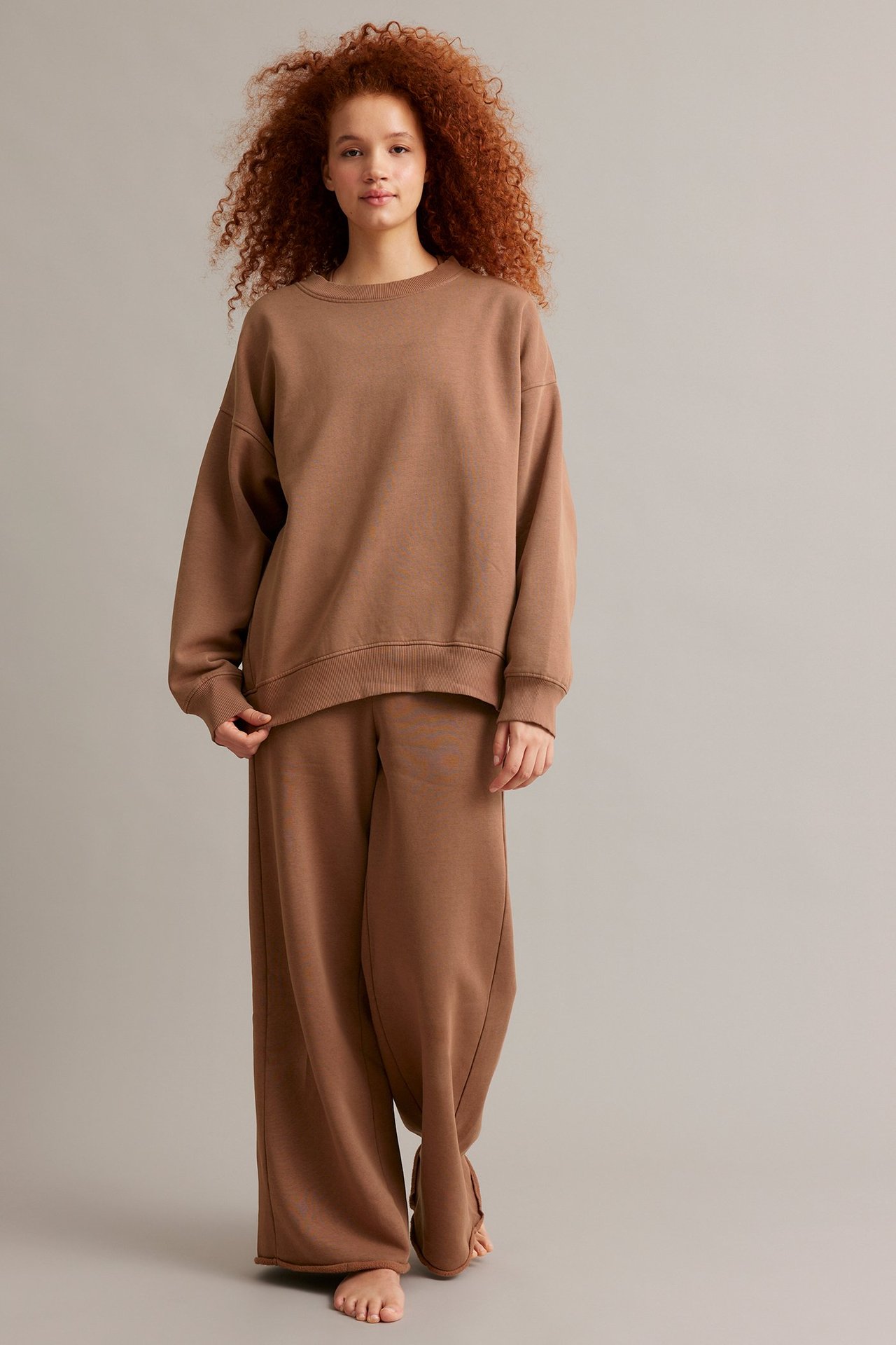 Edestäpäin: nainen ruskeassa, pitkässä collegepaidassa ja yhteensopivissa collegehousuissa.