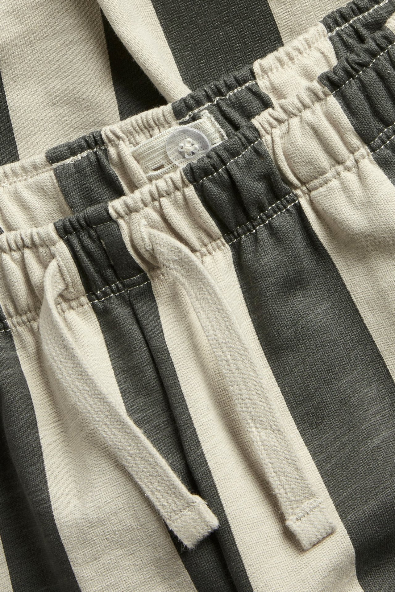 Zbliżenie paska dziecięcych dresów w ciemnoszare i jasnobeżowe paski ze sznurkiem.