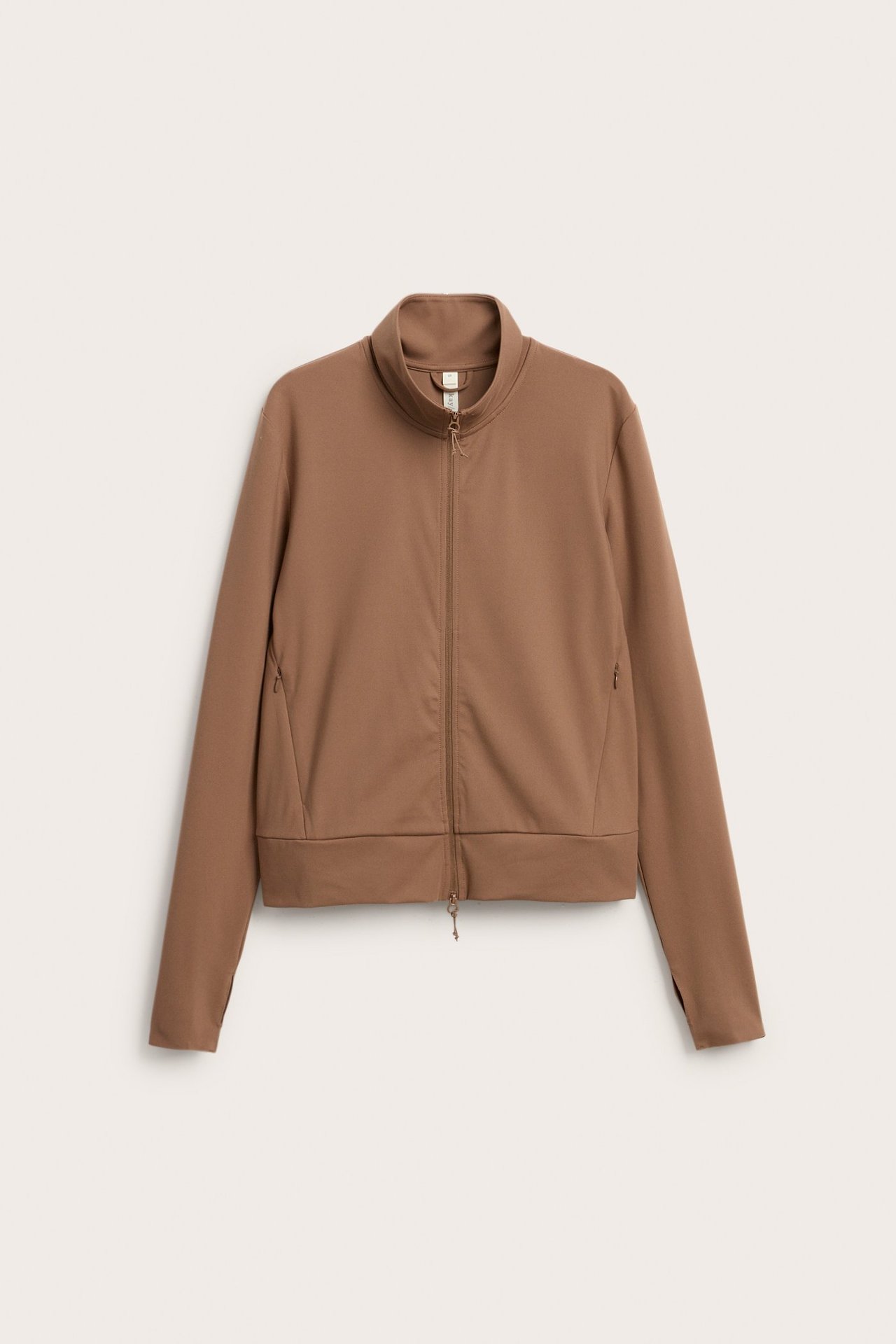 Front view: Brun träningsjacka med ståkrage, hel dragkedja, tumhål och fickor med dragkedja.