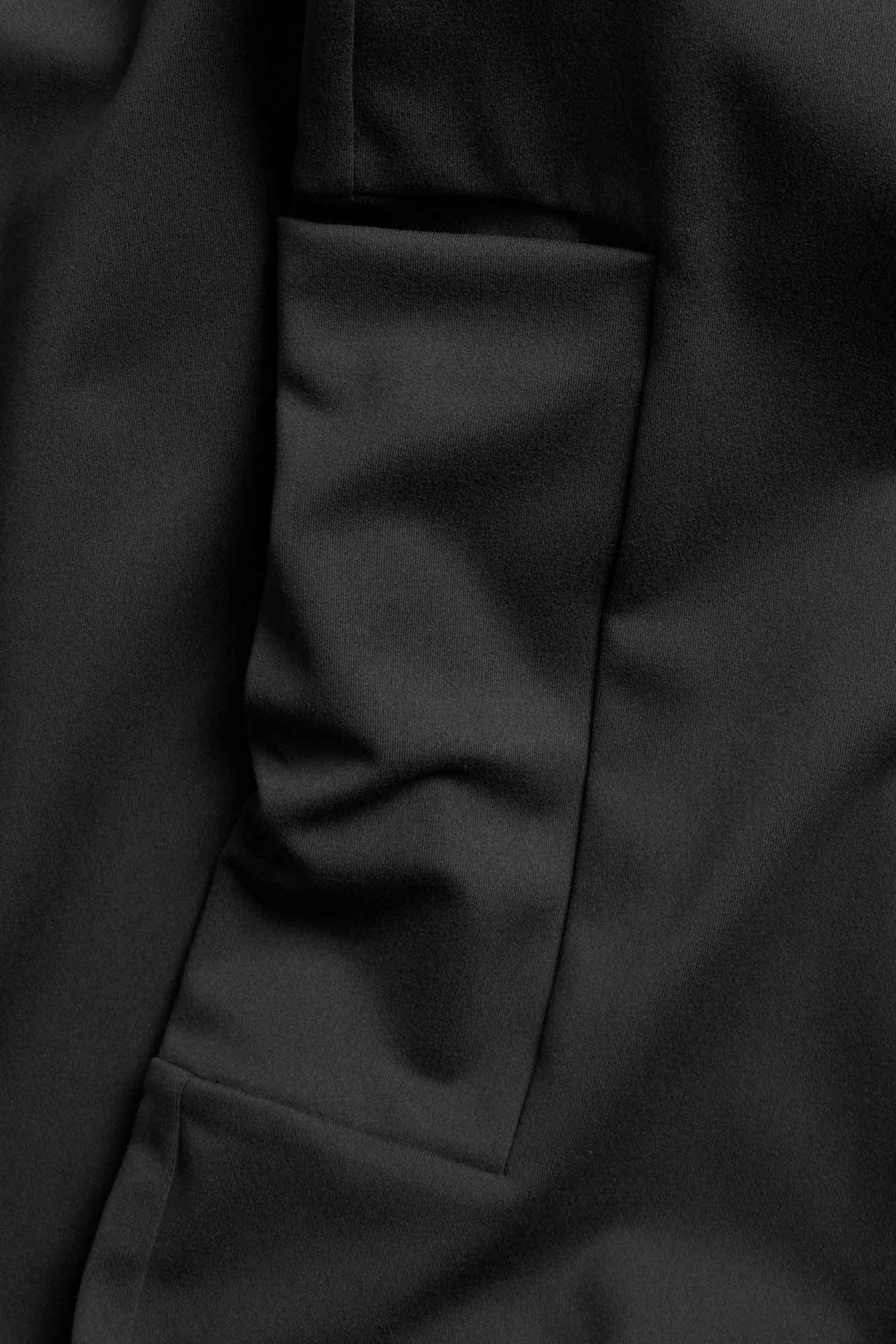 Lähikuva mustista bootcut-treenitrikoista, joissa polyesteri-elastaanista valmistettu reisitasku.