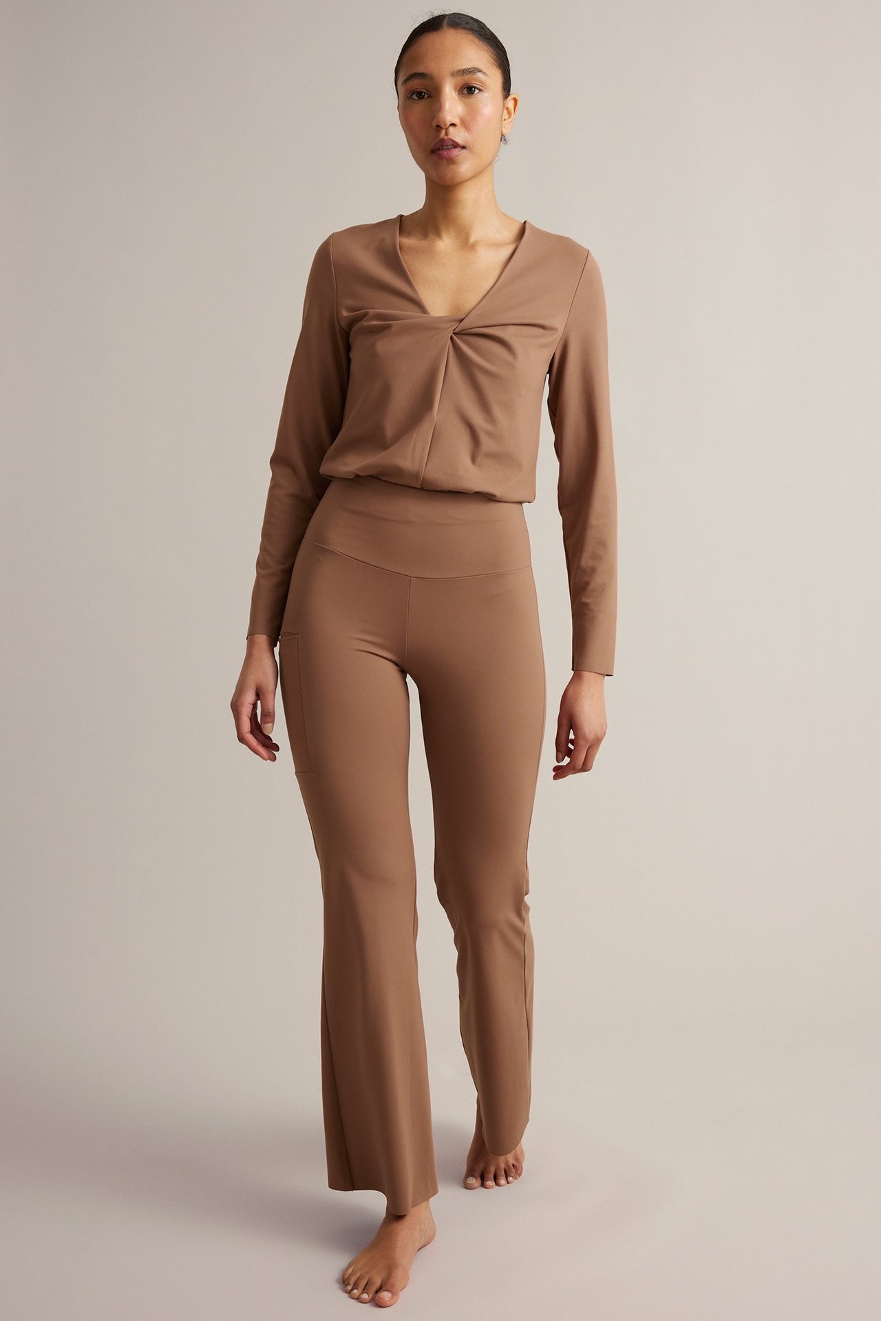 Widok z przodu: Kobieta w brązowych legginsach treningowych bootcut z kieszenią i pasującym topem.