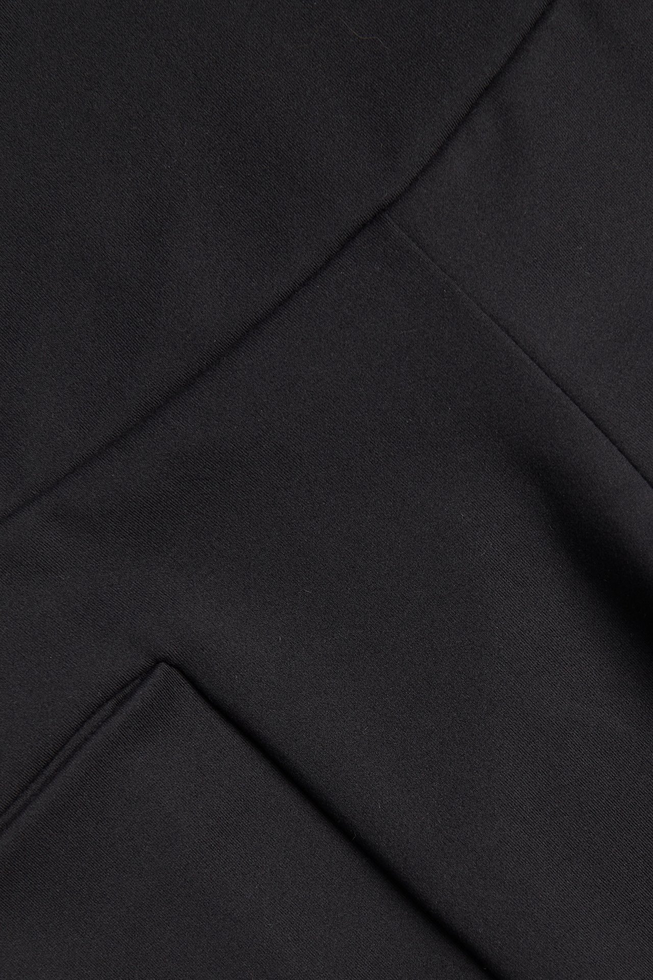 Zbliżenie na czarny, elastyczny materiał szortów kolarskich, ukazujące szew i boczną kieszeń.