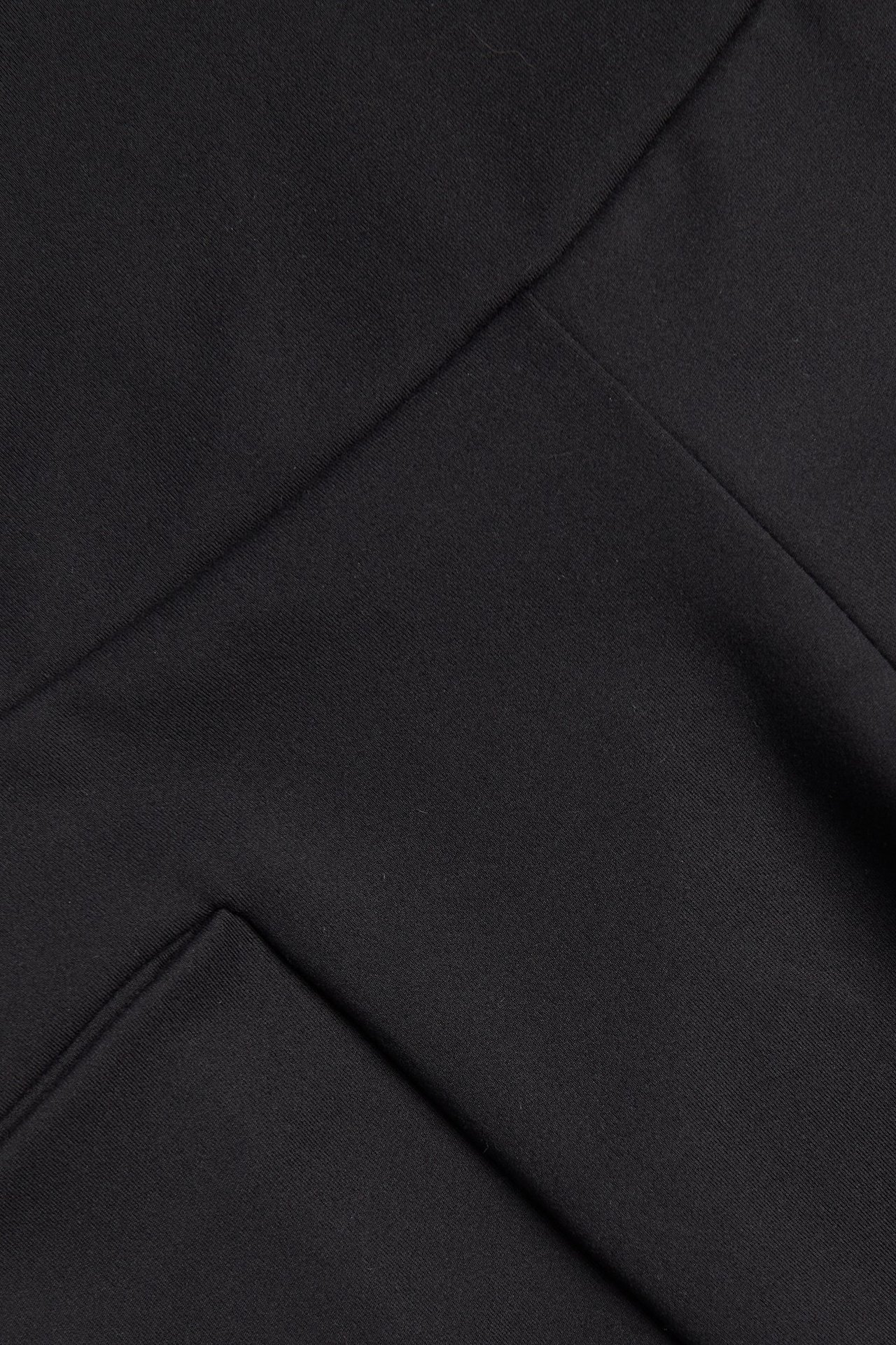 Zbliżenie na czarny, elastyczny materiał szortów kolarskich, ukazujące szew i boczną kieszeń.