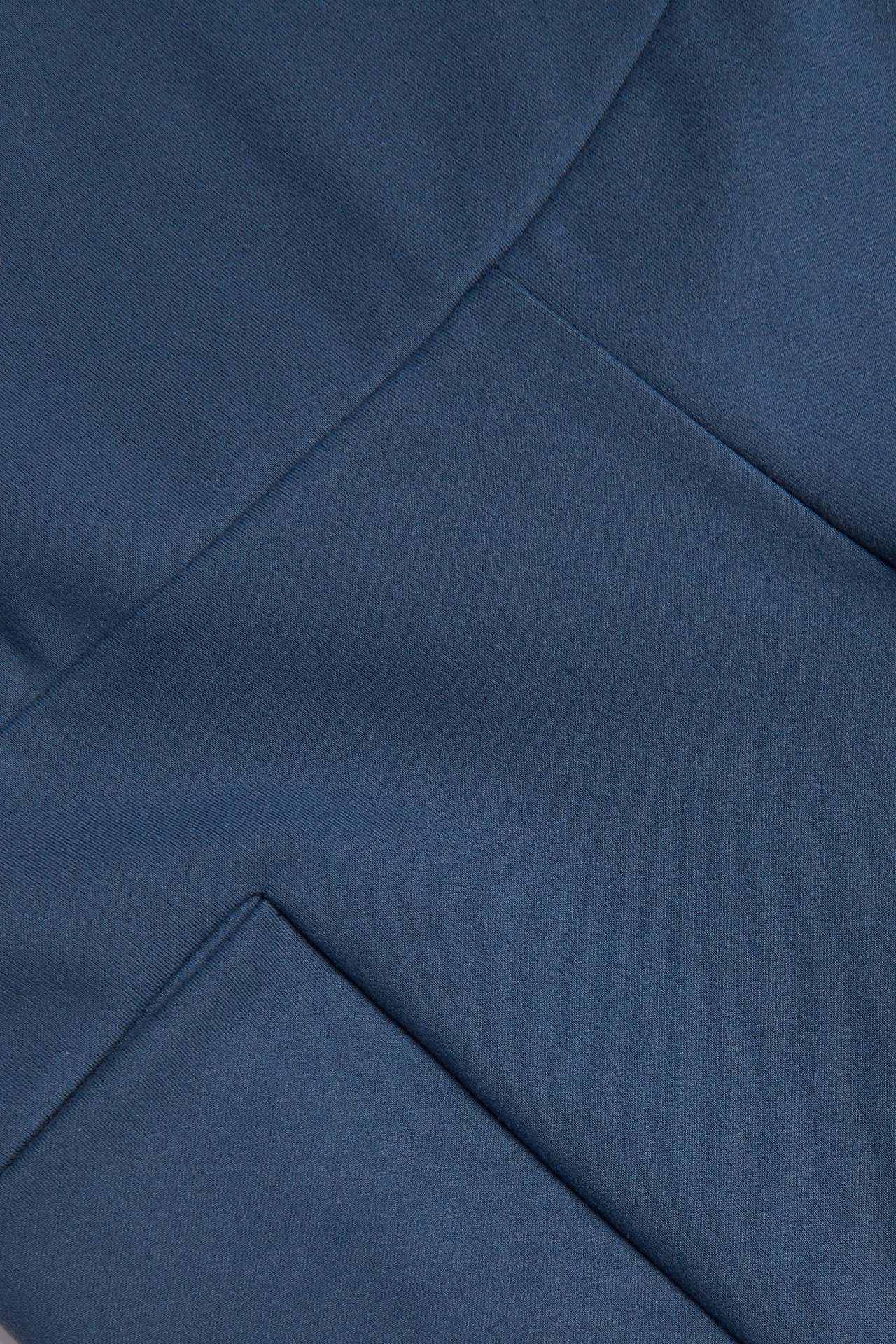 Zbliżenie na niebieskie szorty kolarskie z miękkiego dżerseju ze stretchem, widocznymi szwami i kieszenią na telefon.