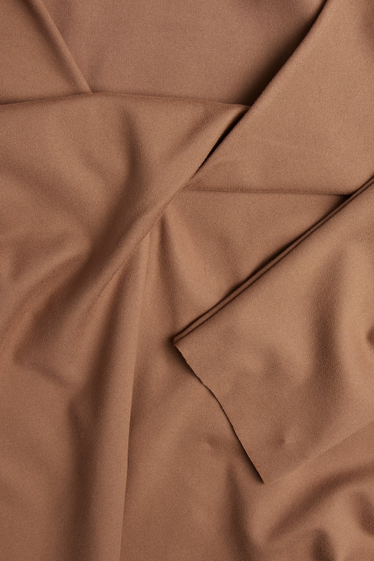 Nærbilde av brun treningstopp i jersey med omslagsdetalj i V-halsen.