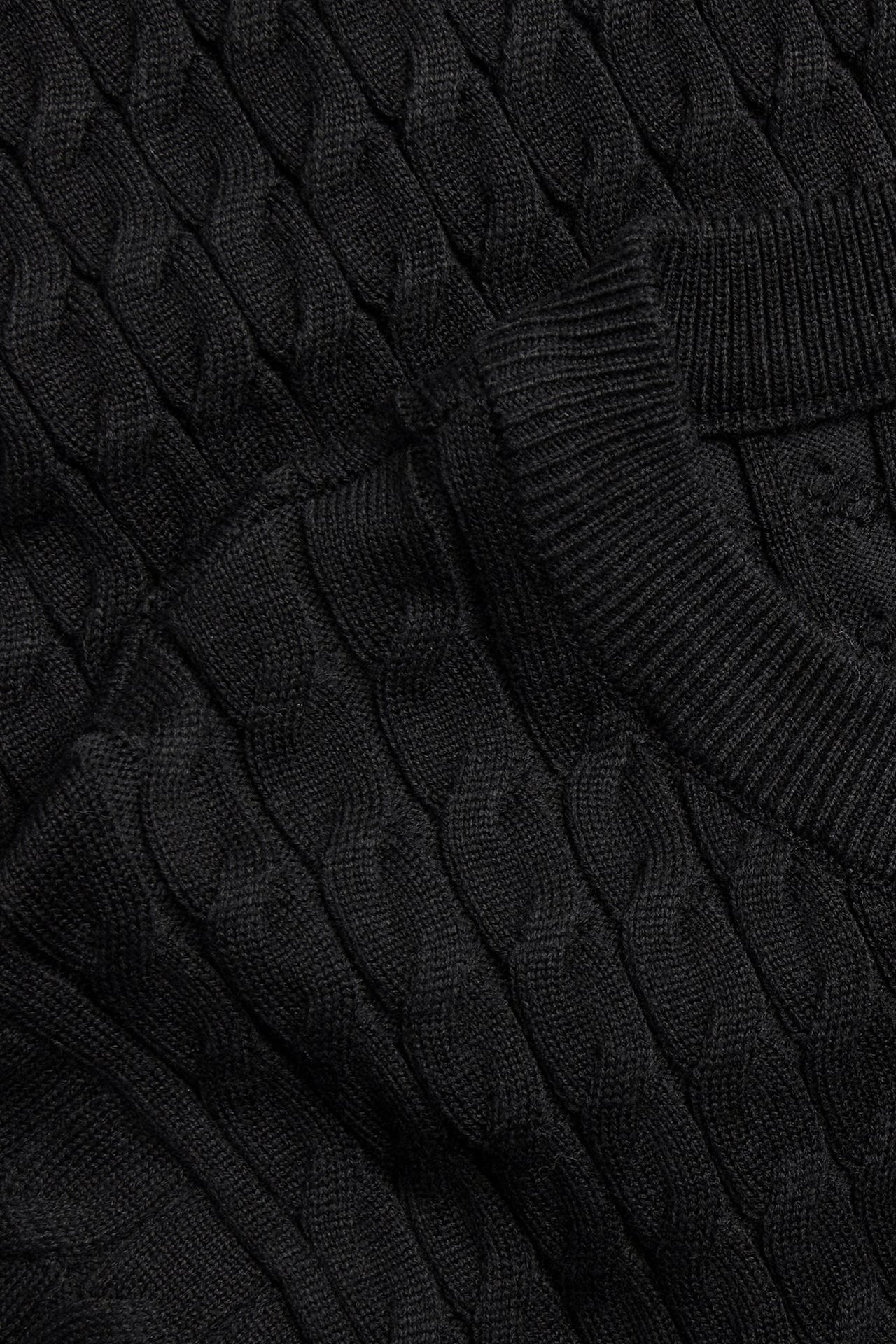 Nærbilde av en svart kabelstrikket kjole med ribbet hals.